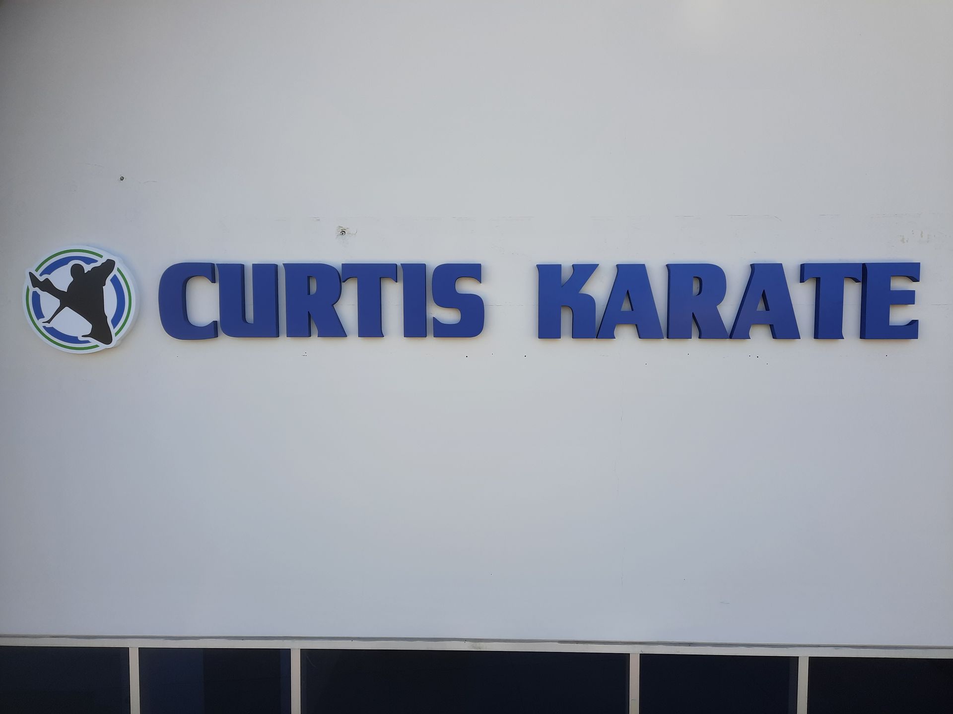 Curtis Karate sign in blue letters on a light wall