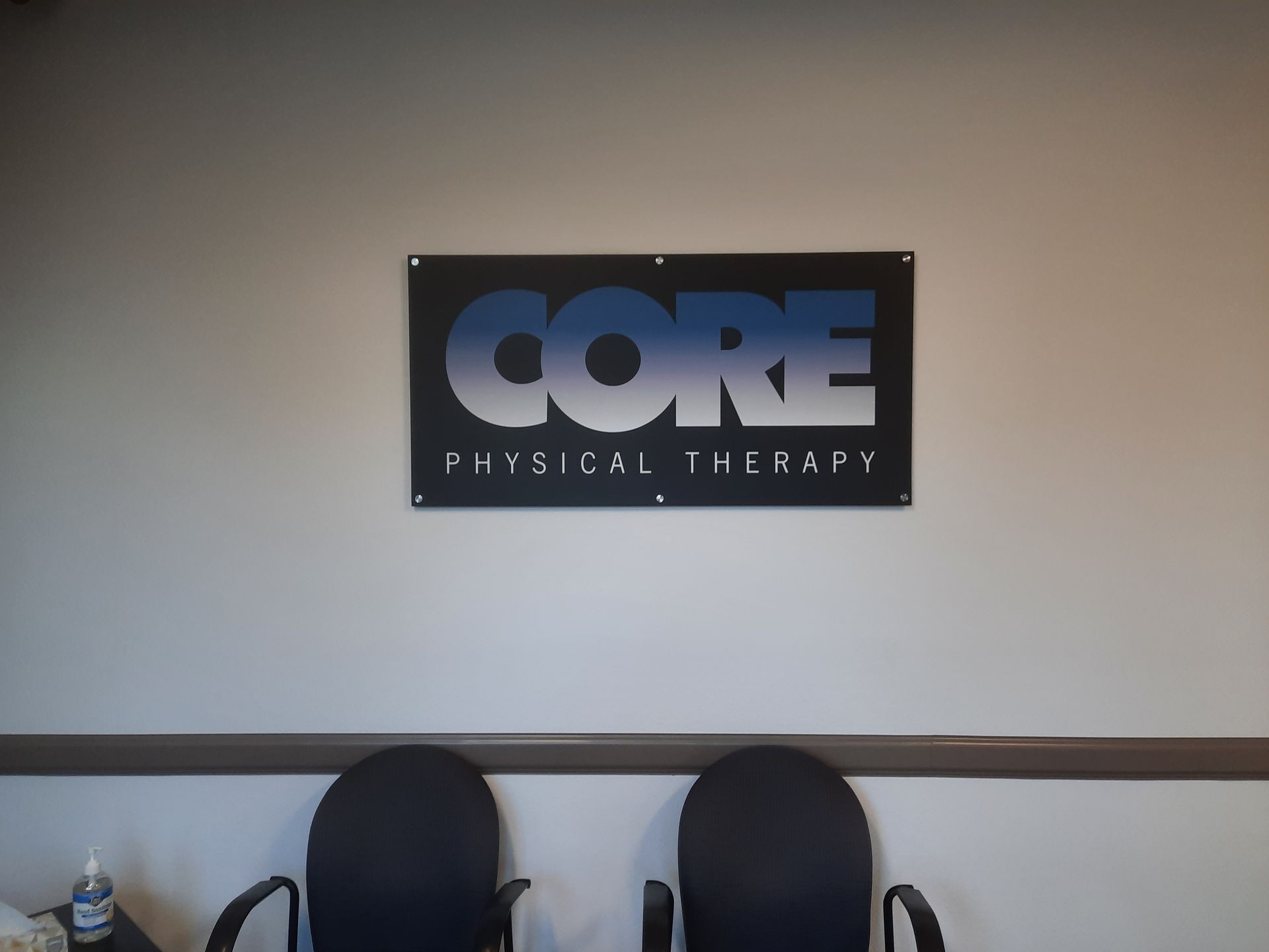 CORE Physical Therapy sign on a wall above two black chairs in a waiting area