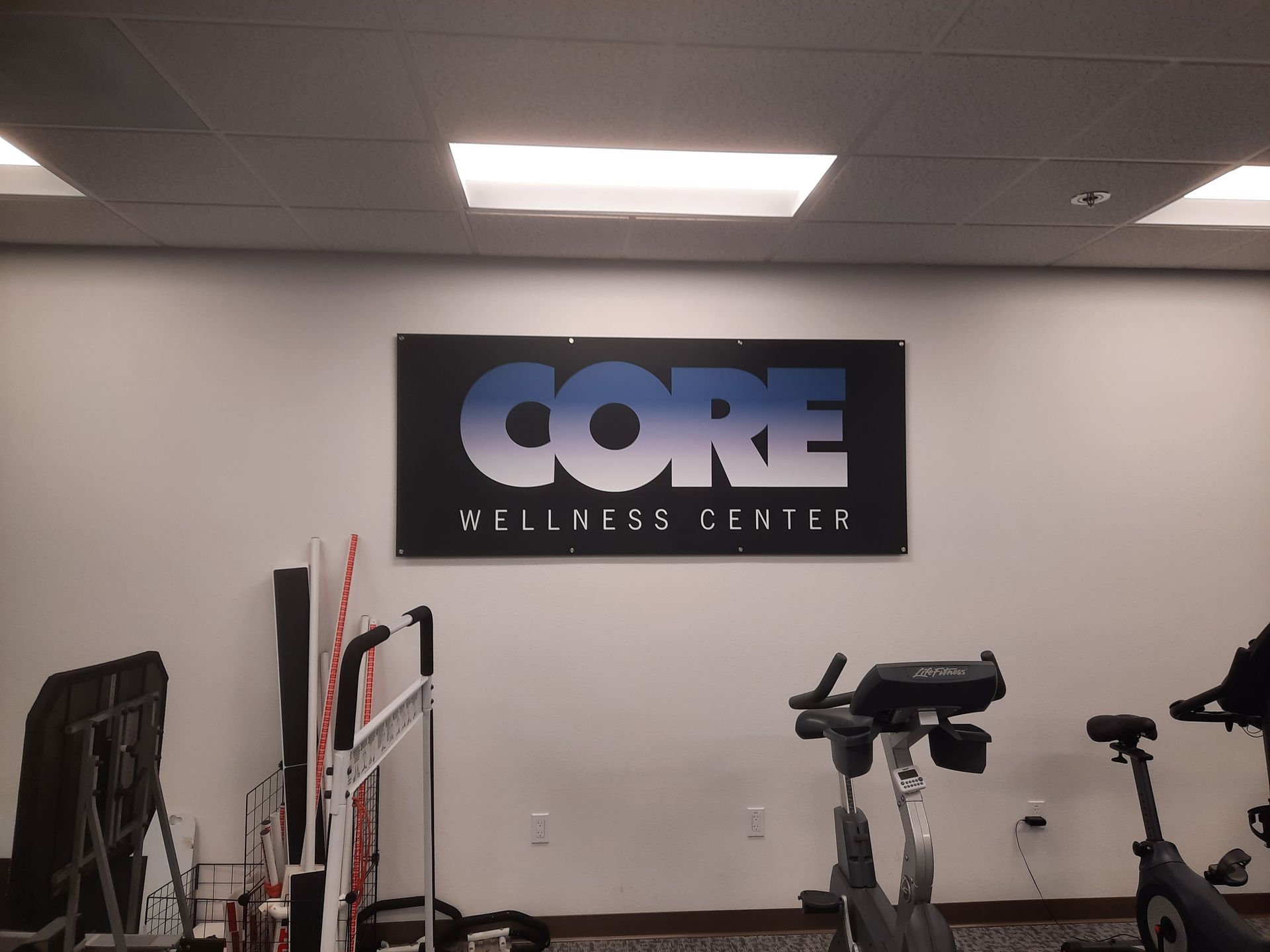 Gym interior with CORE Wellness Center sign and exercise equipment along the wall
