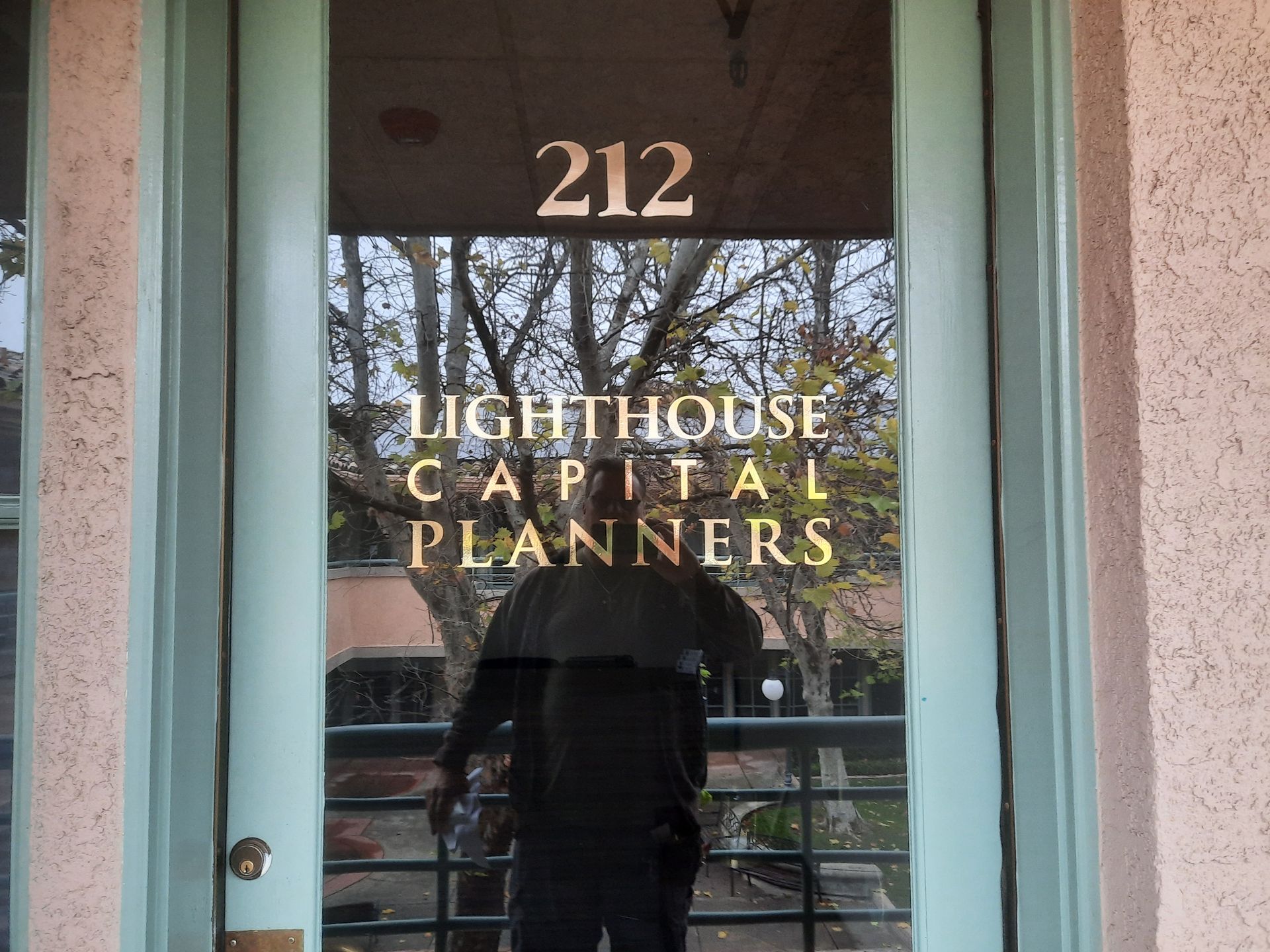 Glass door with room number 212 and gold lettering for Lighthouse Capital Planners.