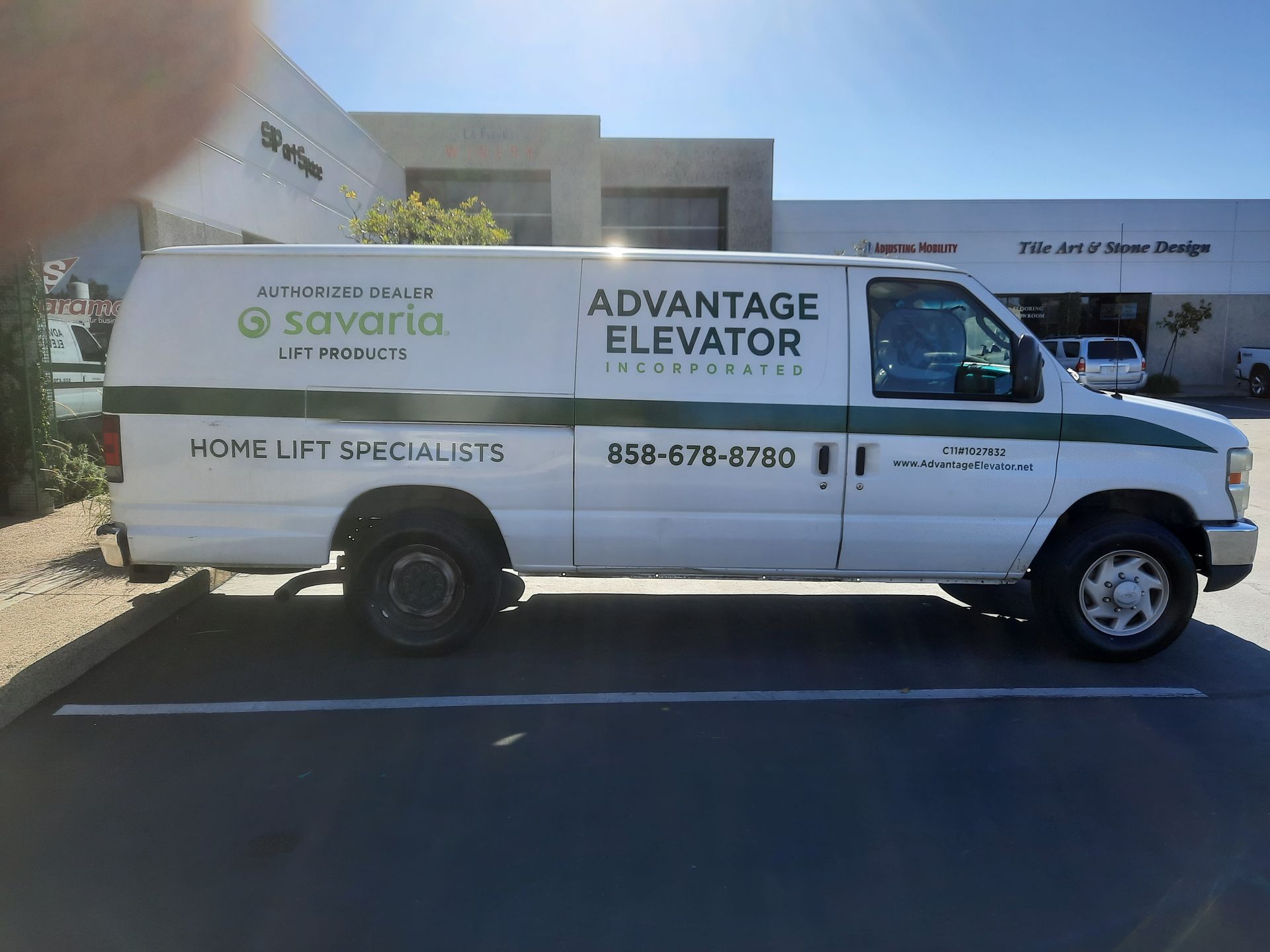 White Advantage Elevator van parked outside a building, with company branding and contact information on the side.