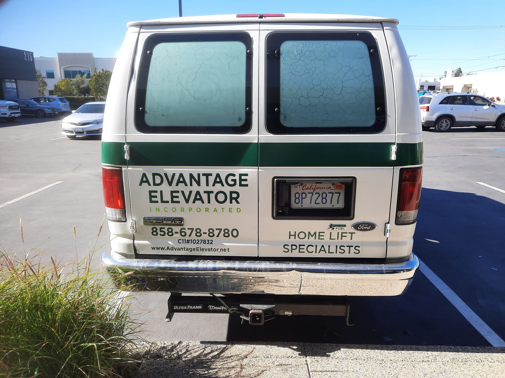 Rear view of an Advantage Elevator service van parked in a lot, with company contact info on the back.