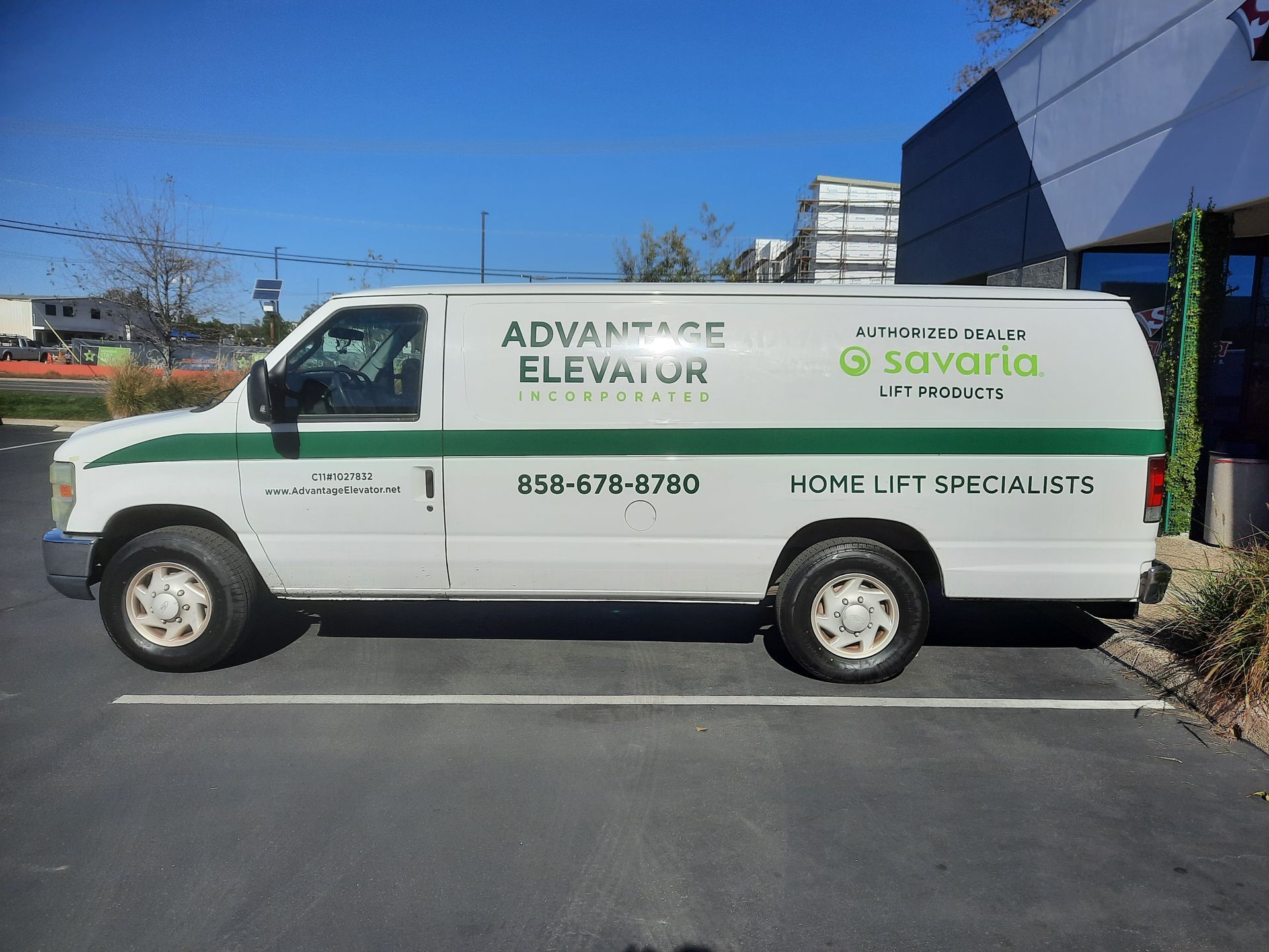 White accessibility service van parked outside, labeled “Advance Elevator” with green accents and contact info.