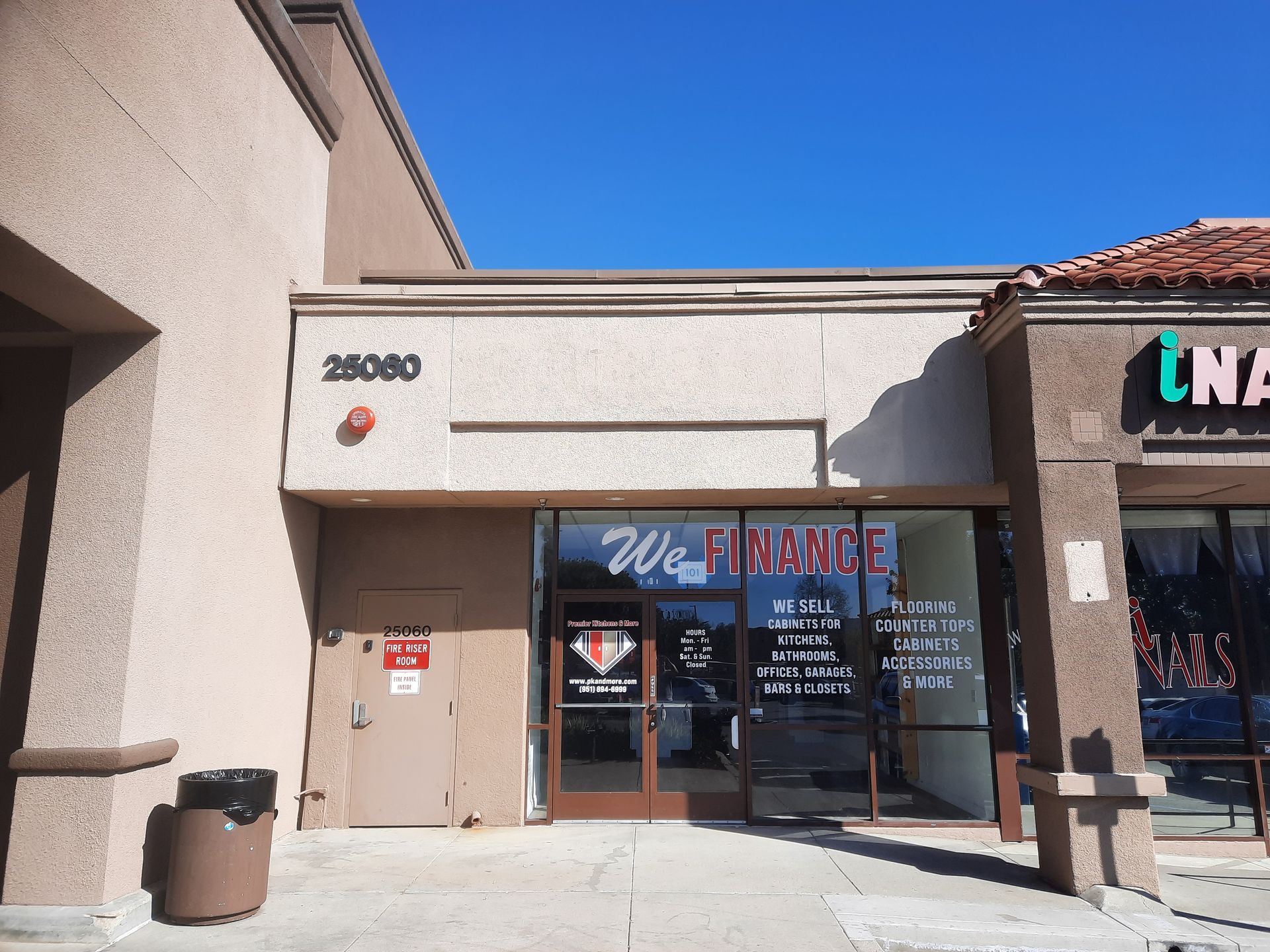 Strip mall storefront with glass doors, blue sky above, and a tan stucco exterior