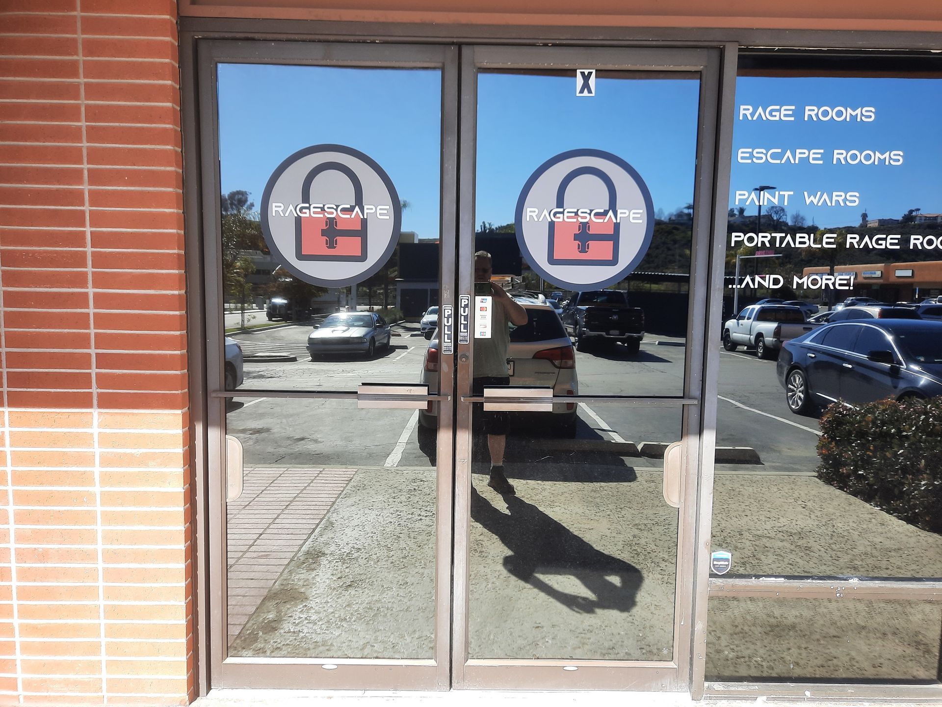 Glass double doors at a storefront entrance with circular decals and white text on the right window.
