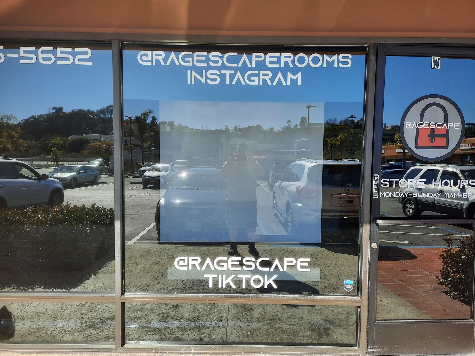 Storefront window with GracescapeRons Instagram and TikTok signs reflected in glass