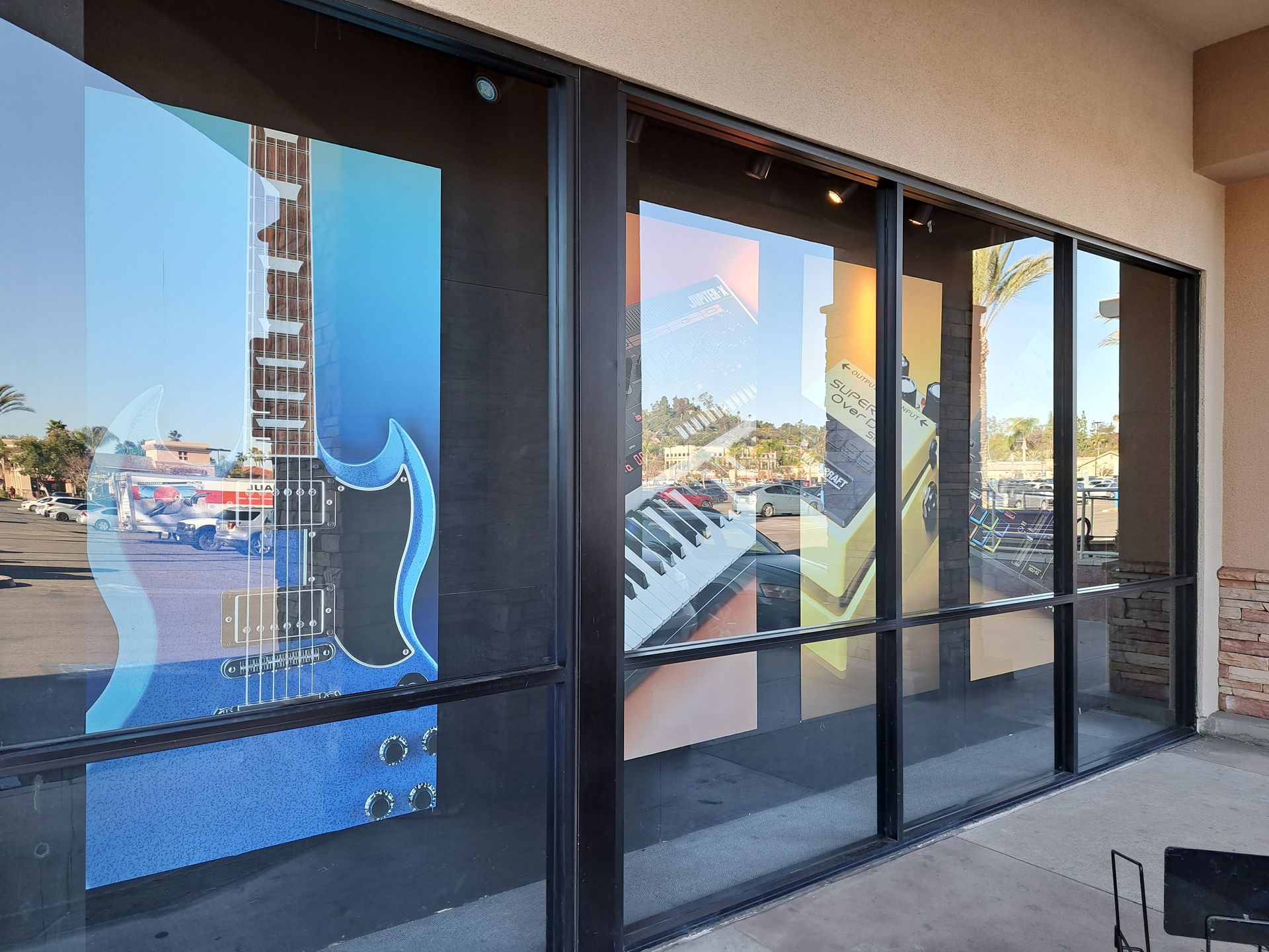 Storefront windows with dark frames reflecting the street and nearby buildings