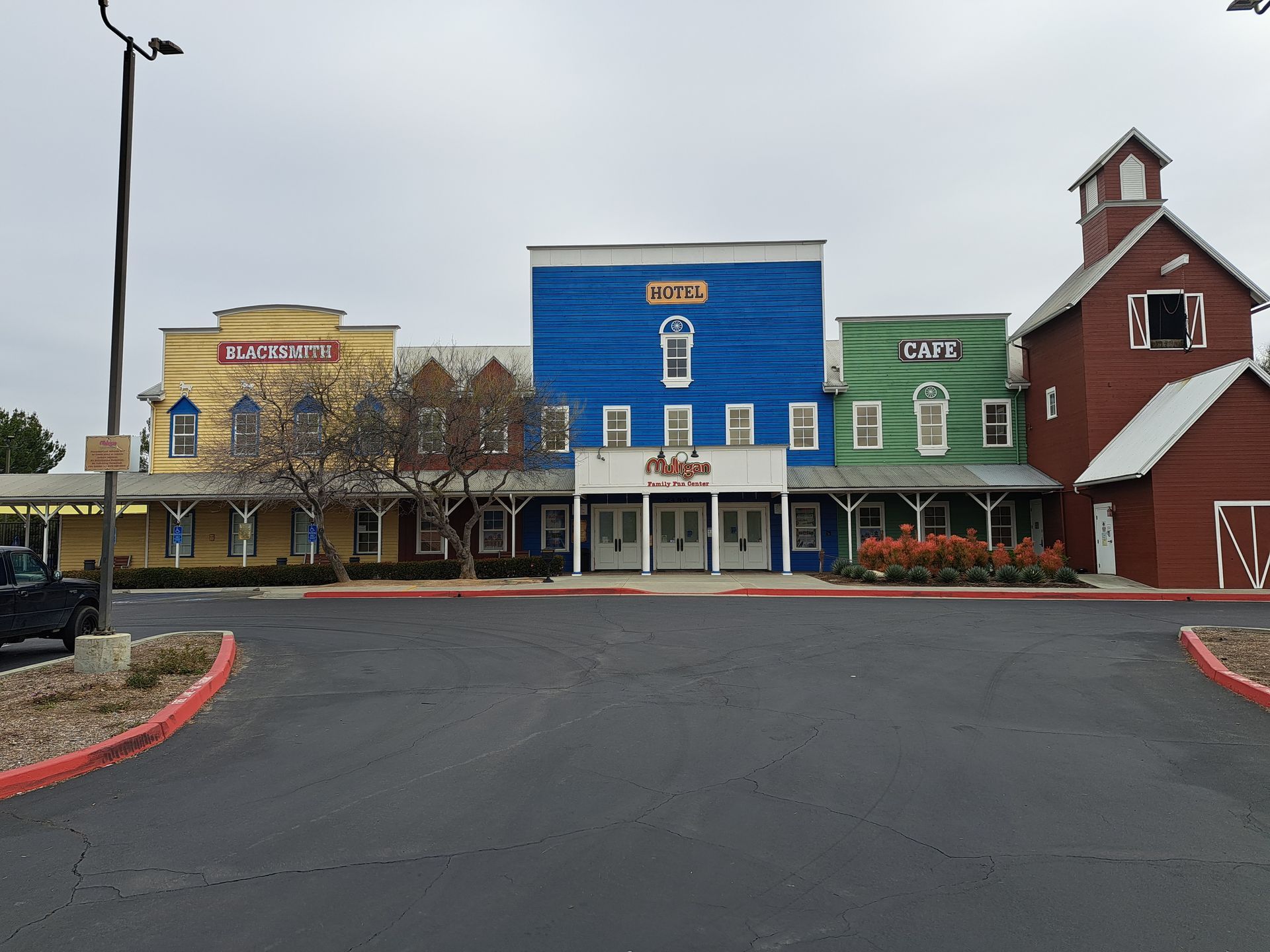 Colorful small-town storefronts with a blue center building and a red barn-style building beside a parking lot