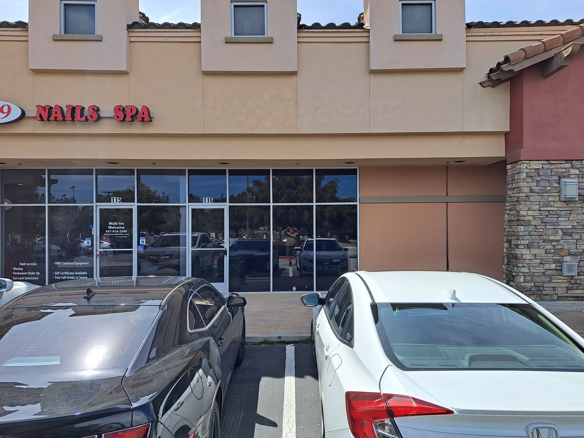 Exterior of a nail spa storefront with two parked cars in front