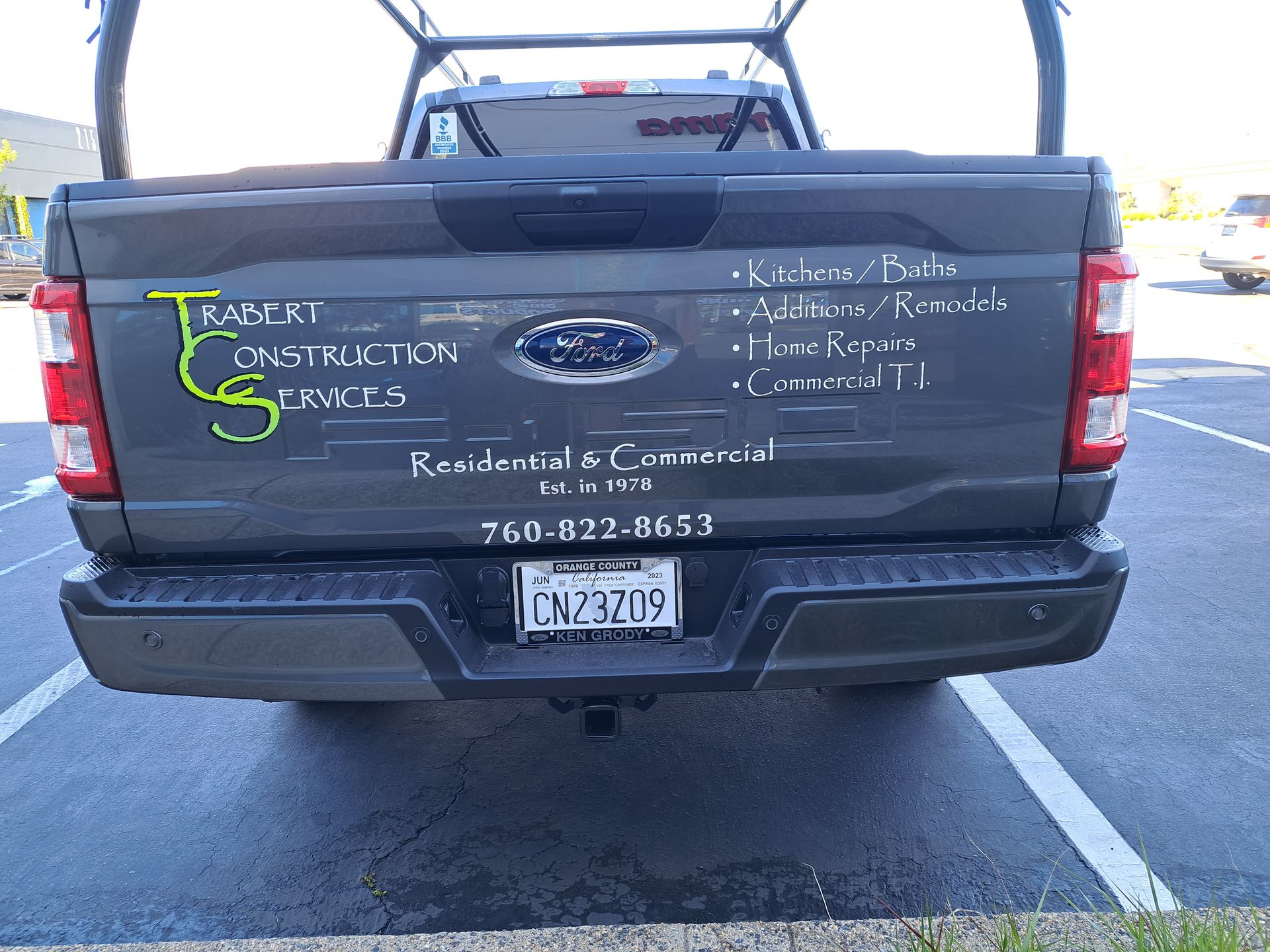 Rear view of a gray pickup truck with a “T Services Construction” logo and contact info on the tailgate.