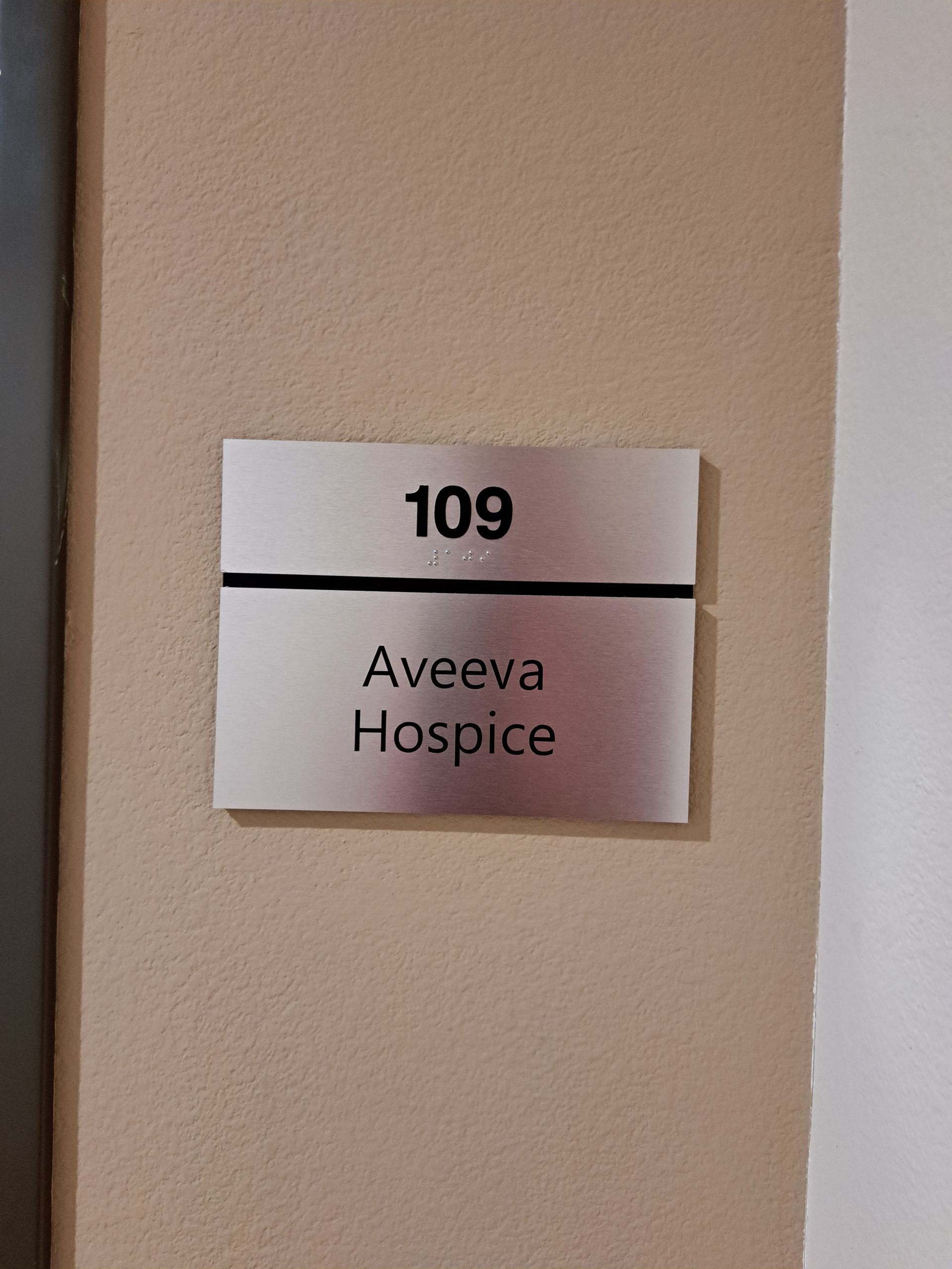 Room sign reading “109” and “Aveva Hospice” on a beige wall.