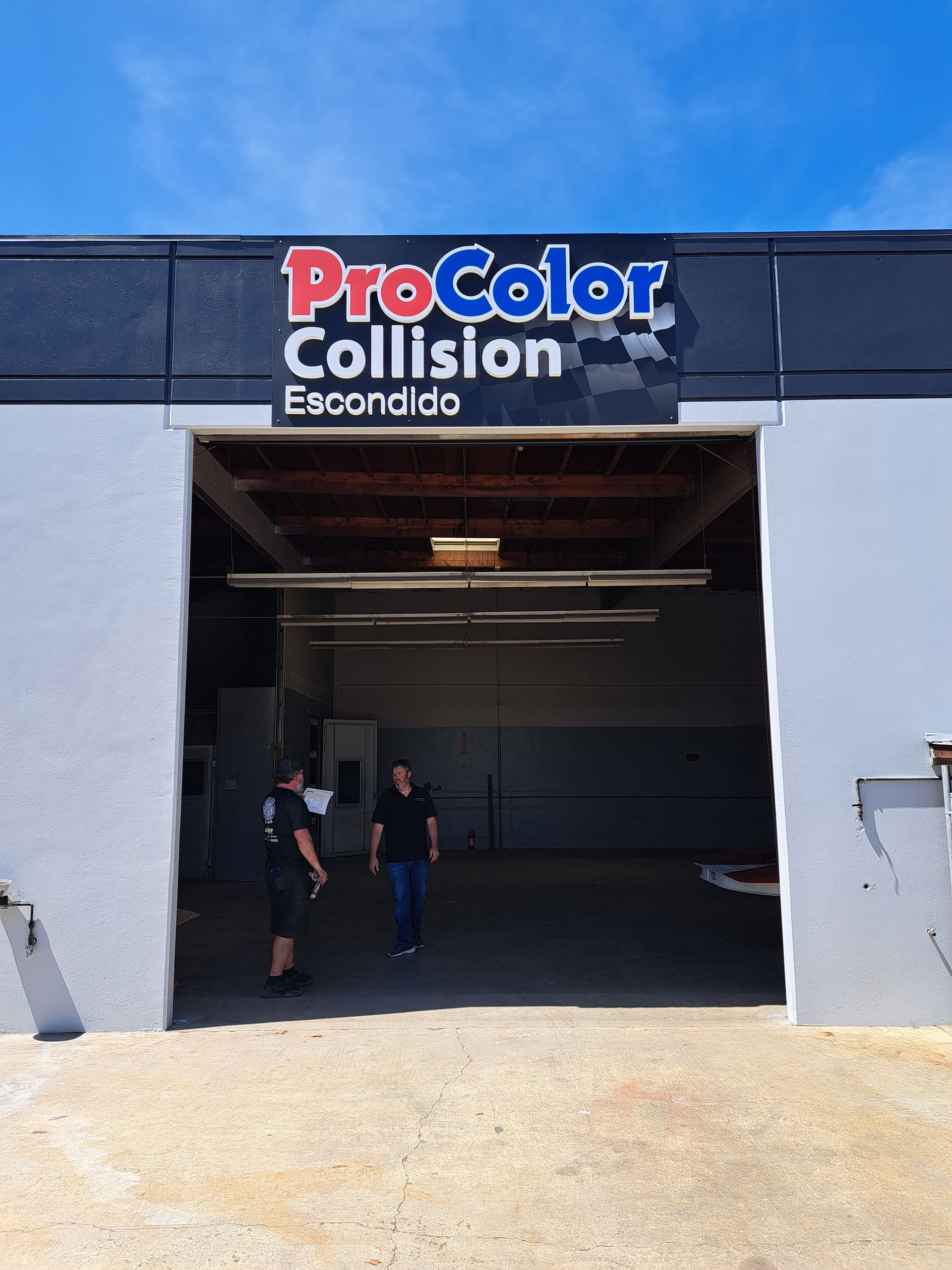 ProColor Collision Escondido storefront with open garage bay and two people standing inside