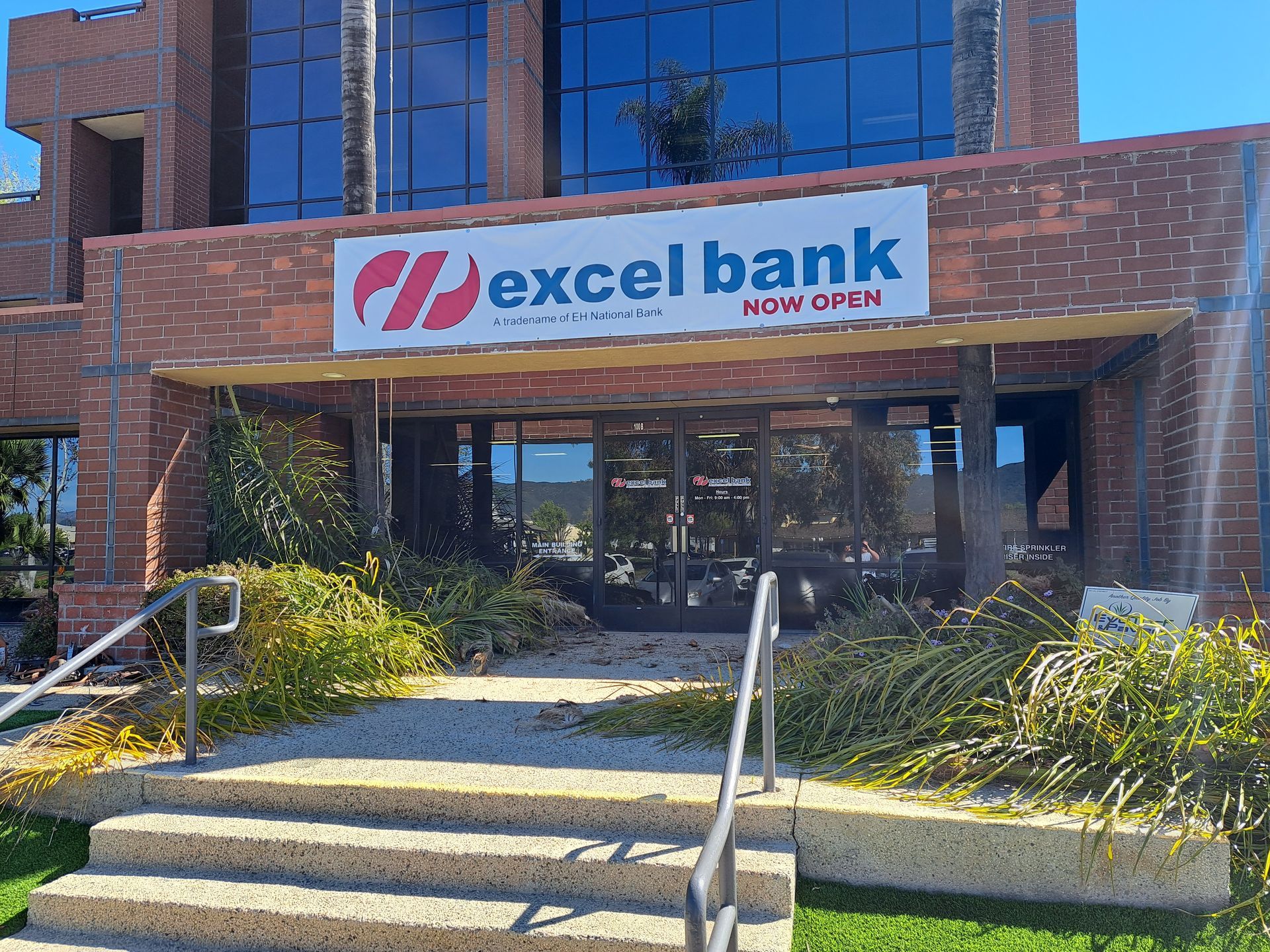 Excel Bank storefront with red-and-blue sign above the entrance and steps leading up to the door