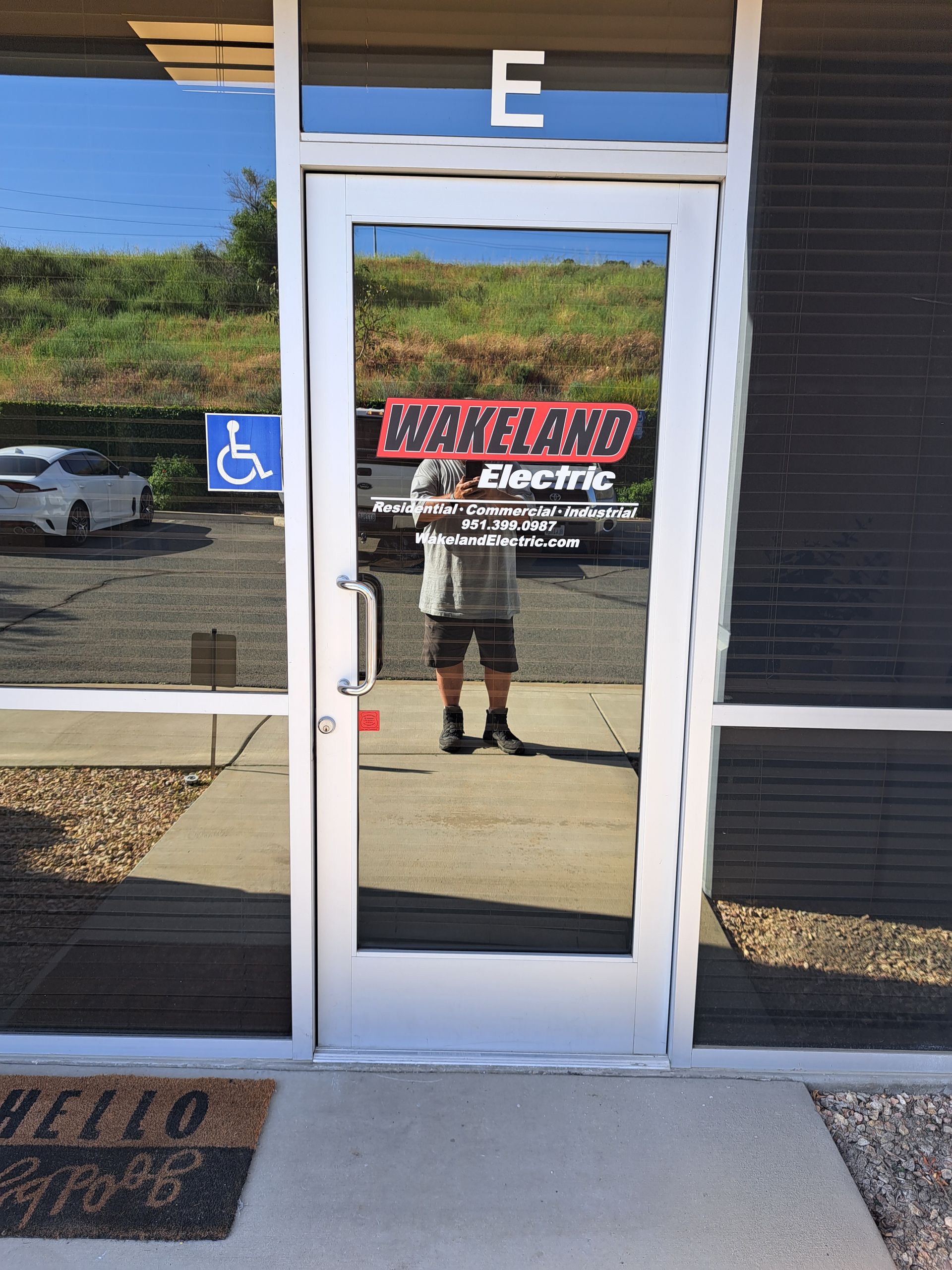 Glass storefront door labeled “WATERLAND” with a person reflected in the center and an accessibility sign nearby