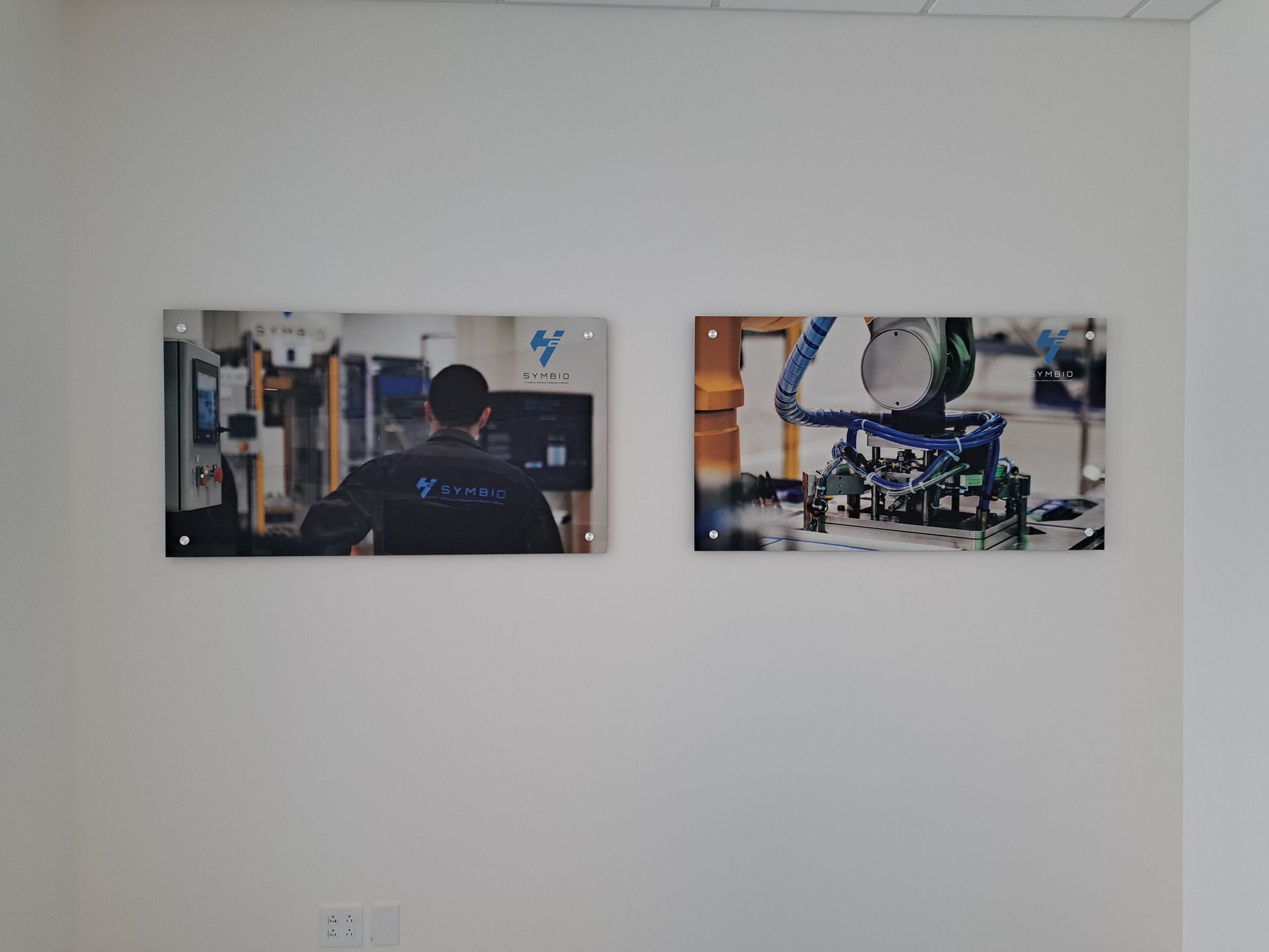 Two wall-mounted industrial work photos in a minimalist white room