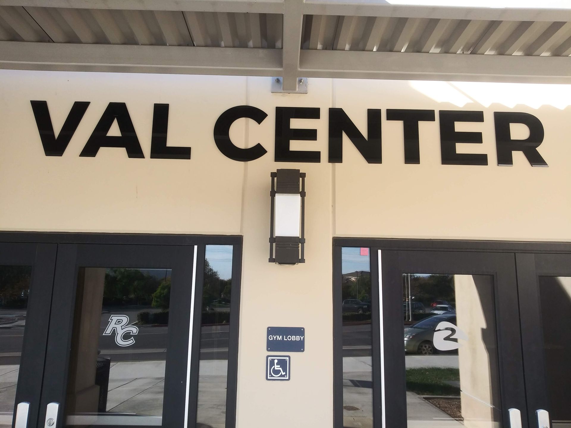 Entrance with bold “VAL CENTER” sign above glass doors on a beige building.