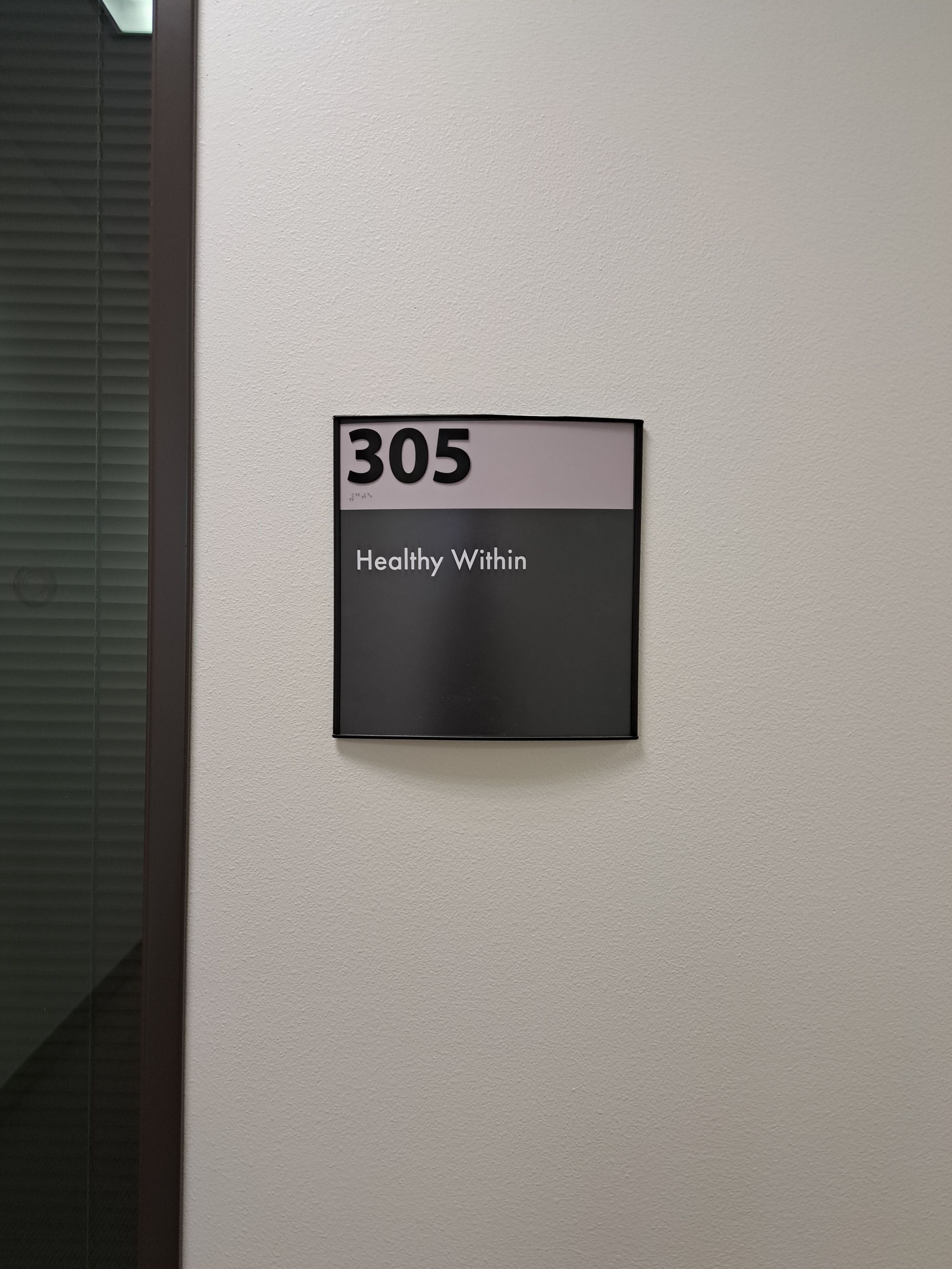 Wall sign reading “305” with “Healthy We’re” on a gray wall near a stairwell.
