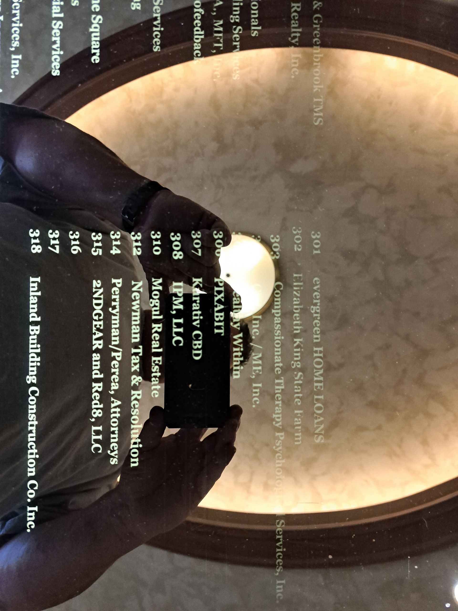 Hands holding a phone toward a glowing circular ceiling light in a dim room.