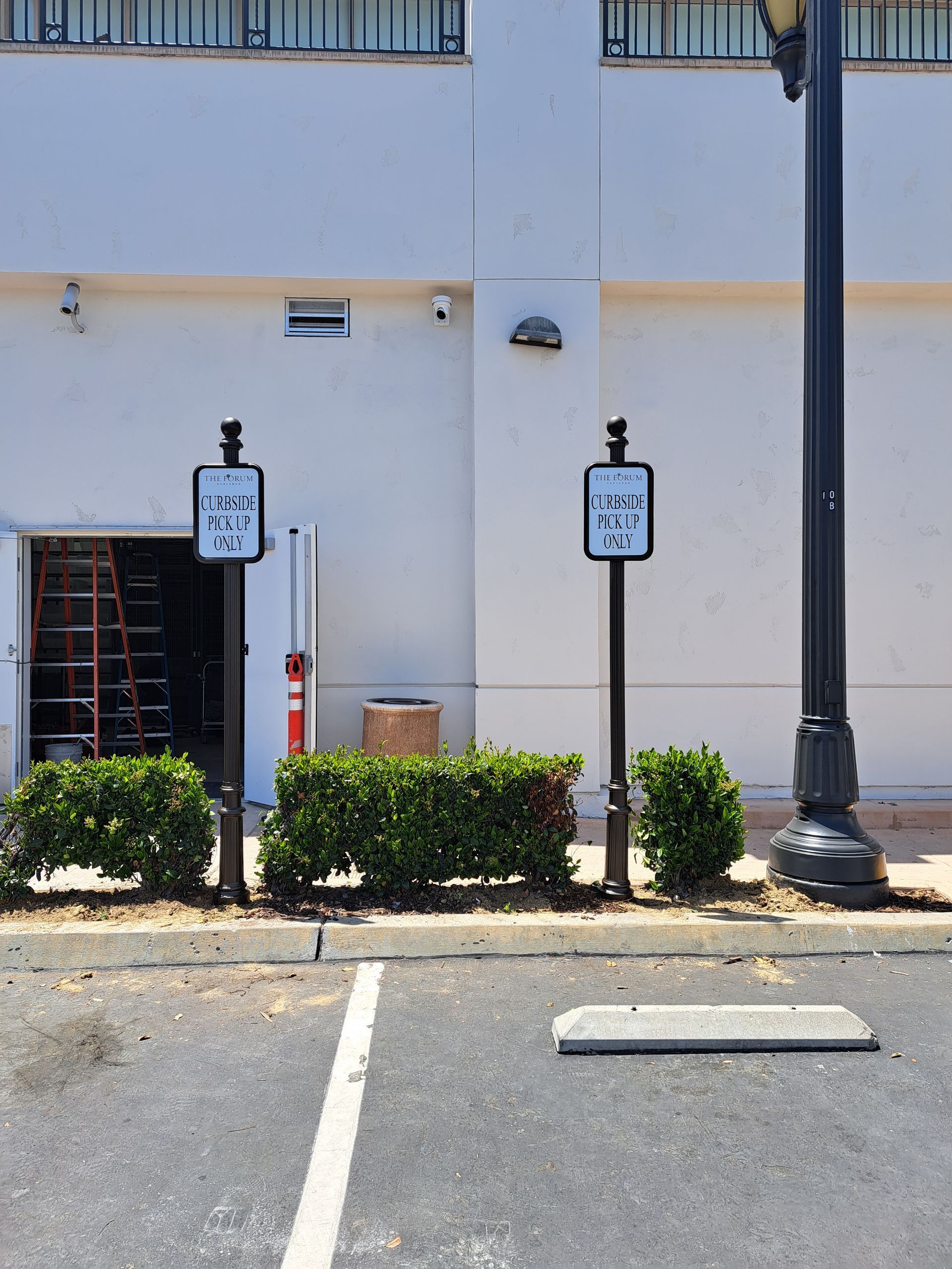 Parking lot with two reserved parking signs beside a white building and black lamppost.