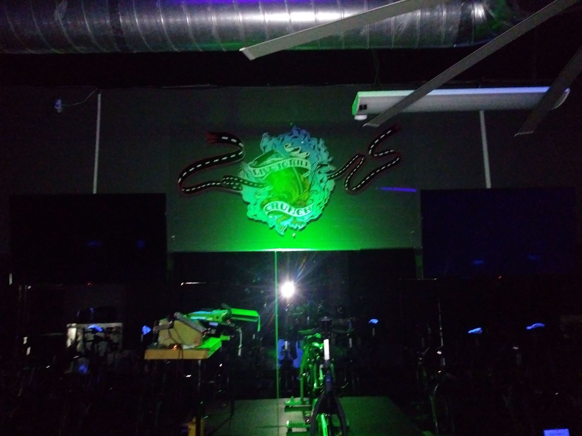 Dim stage with green abstract light projection and dark equipment in a nightclub-like venue