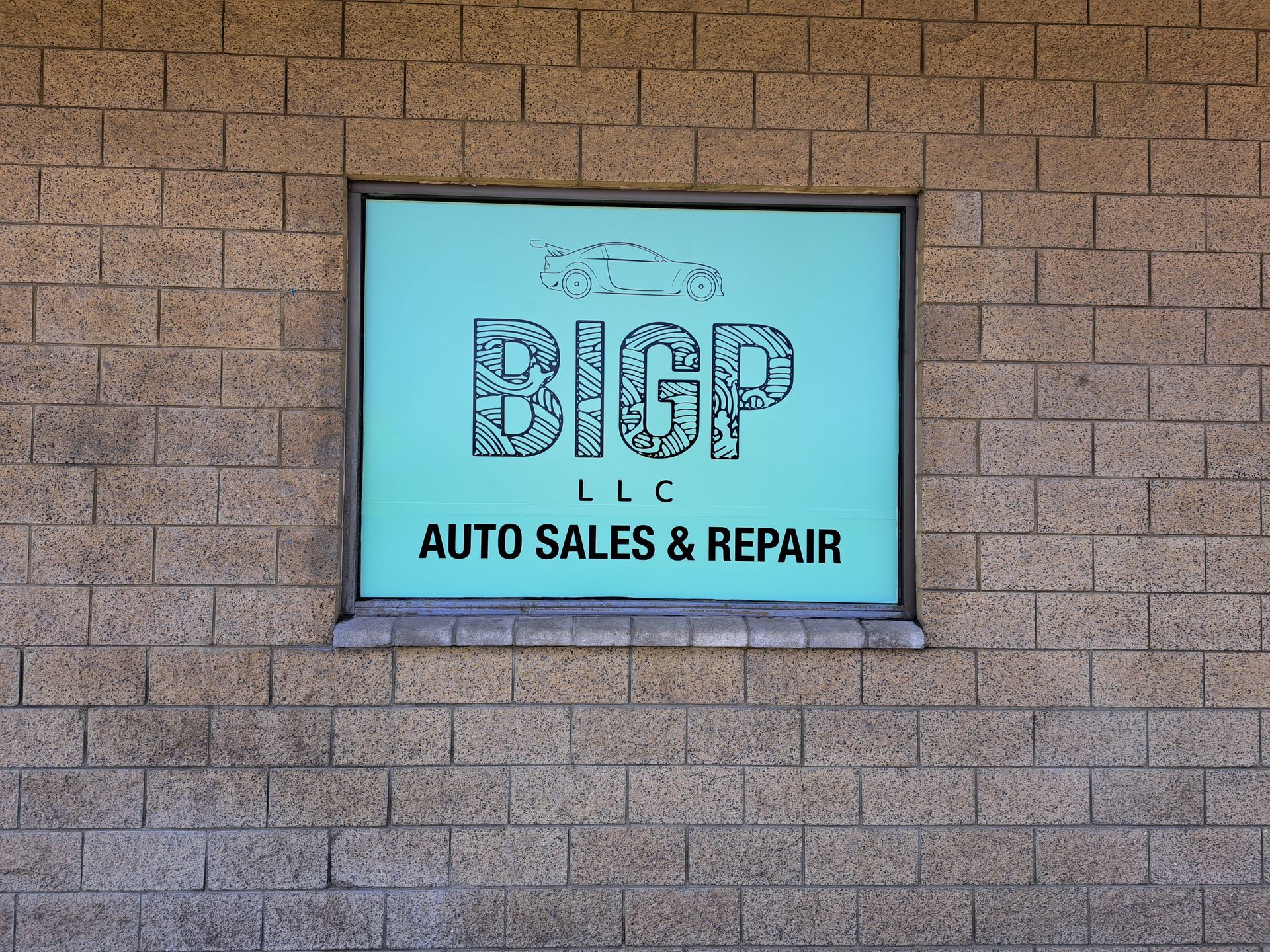 Sign for BICP Auto Sales & Repair on a brick wall, with a blue background and black lettering
