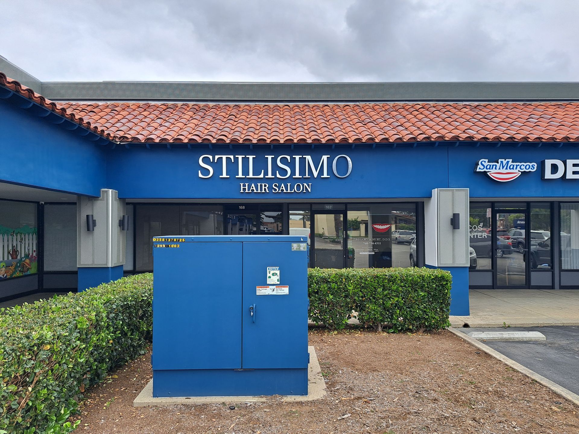 Stilisimo Hair Salon storefront with blue facade and utility box in front