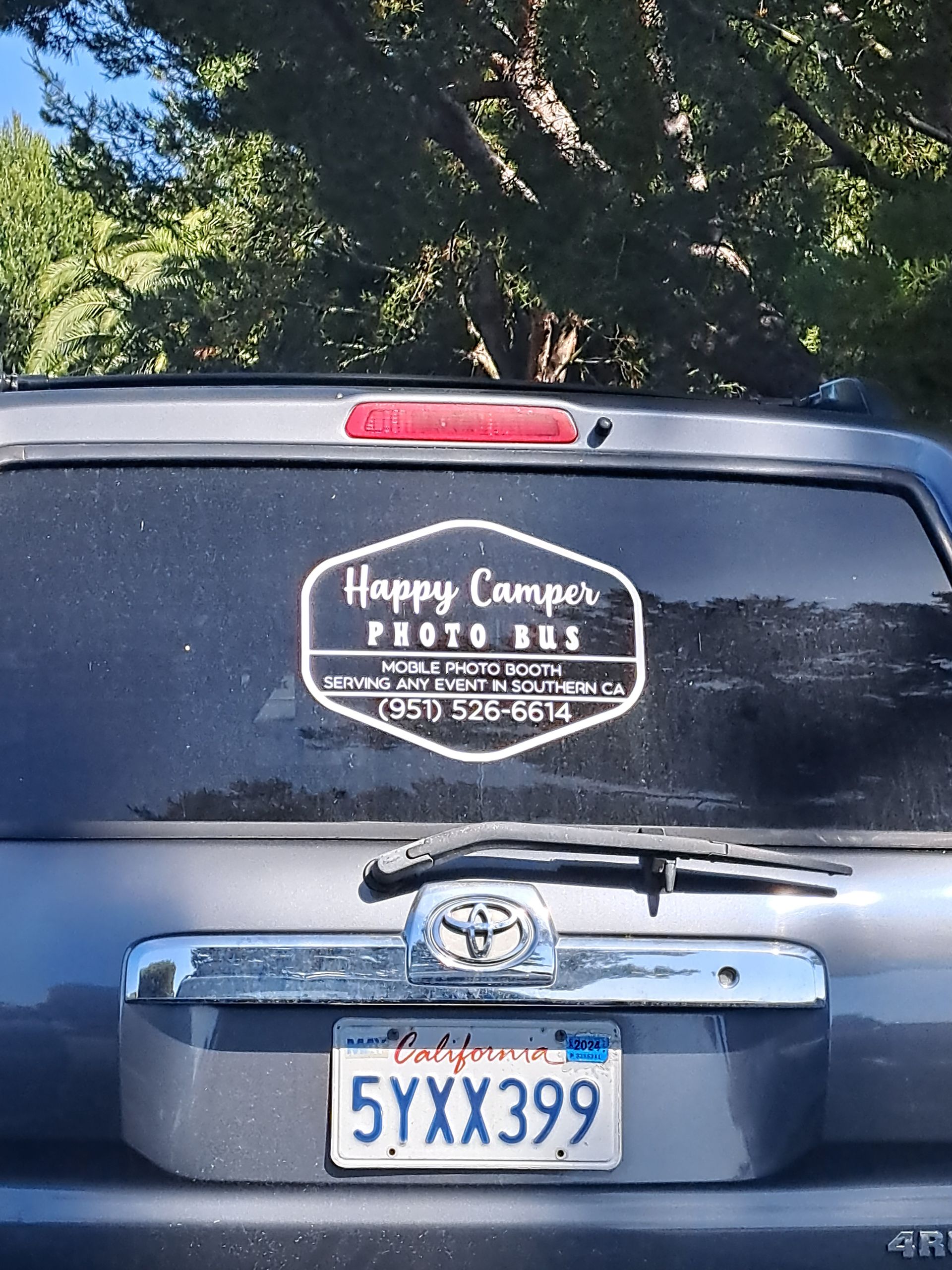 Rear of black SUV with California plate and a Happy Campers sticker on the rear window