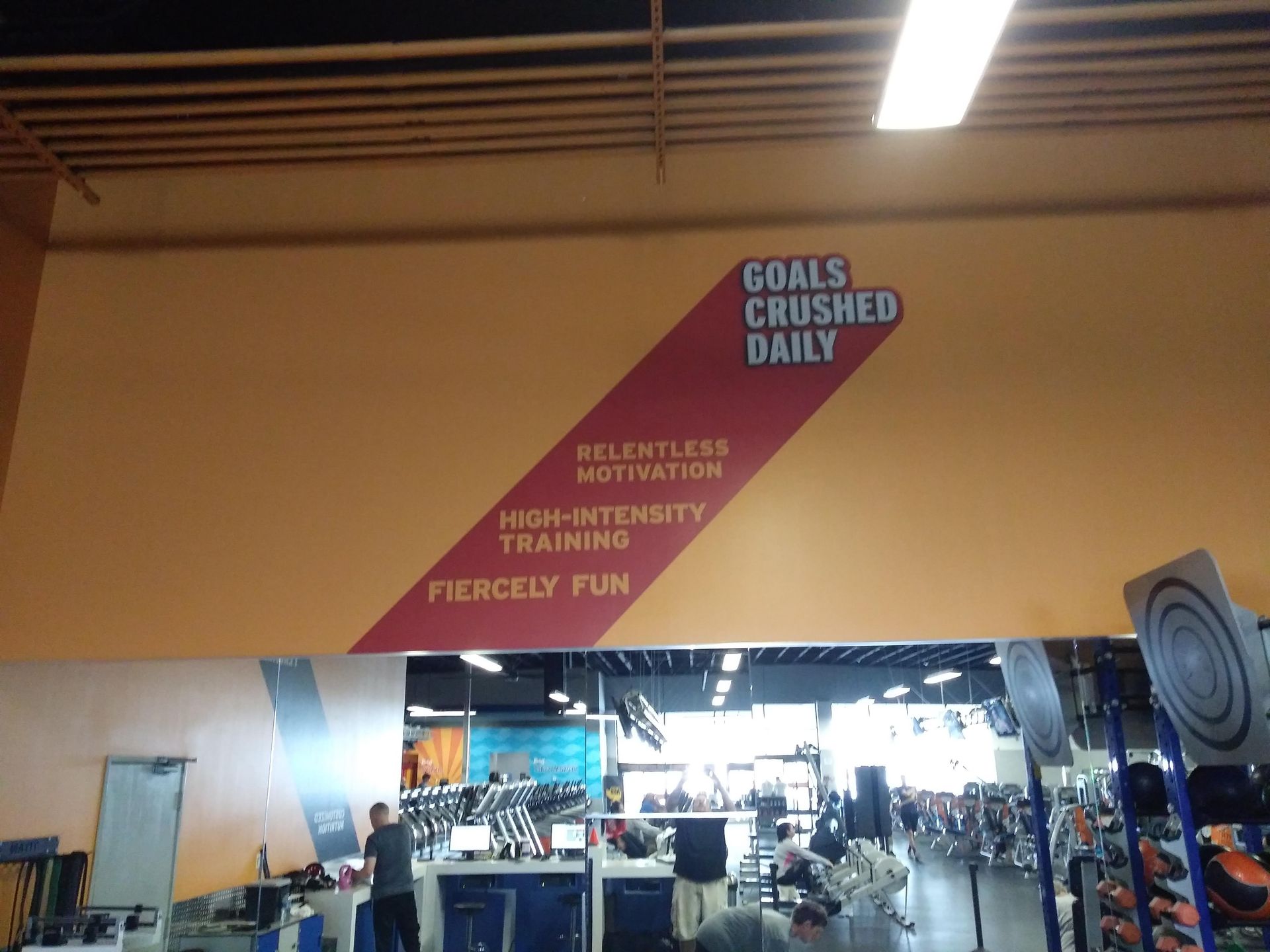 Gym wall mural with “Goals, crushed, daily” and “Relentless, high-intensity, training, fiercely fun” text
