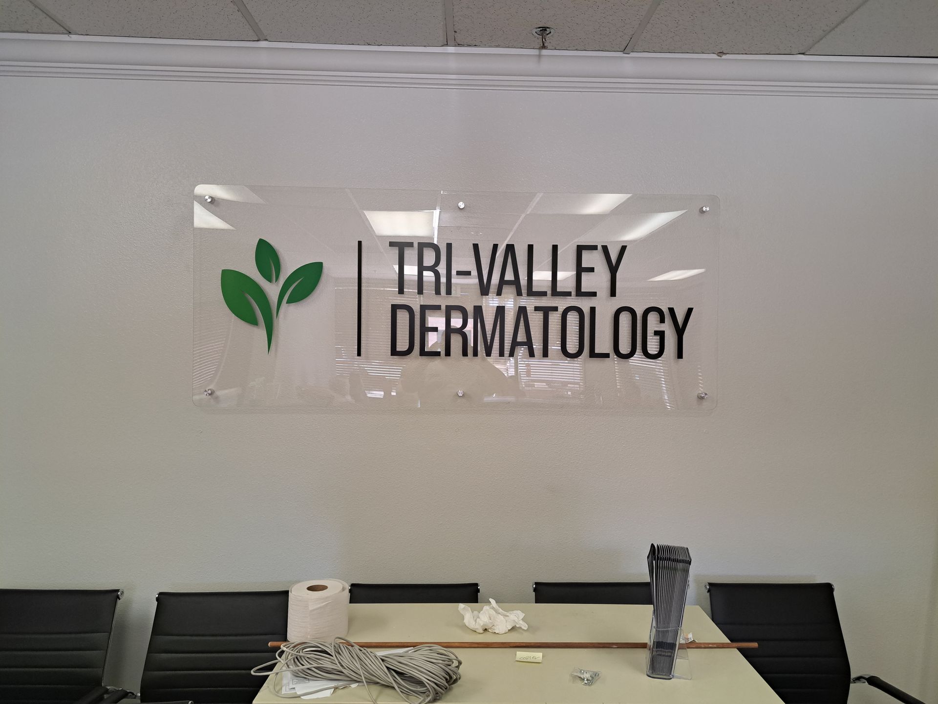 Tri-Valley Dermatology sign on a wall behind a reception desk with chairs and a countertop