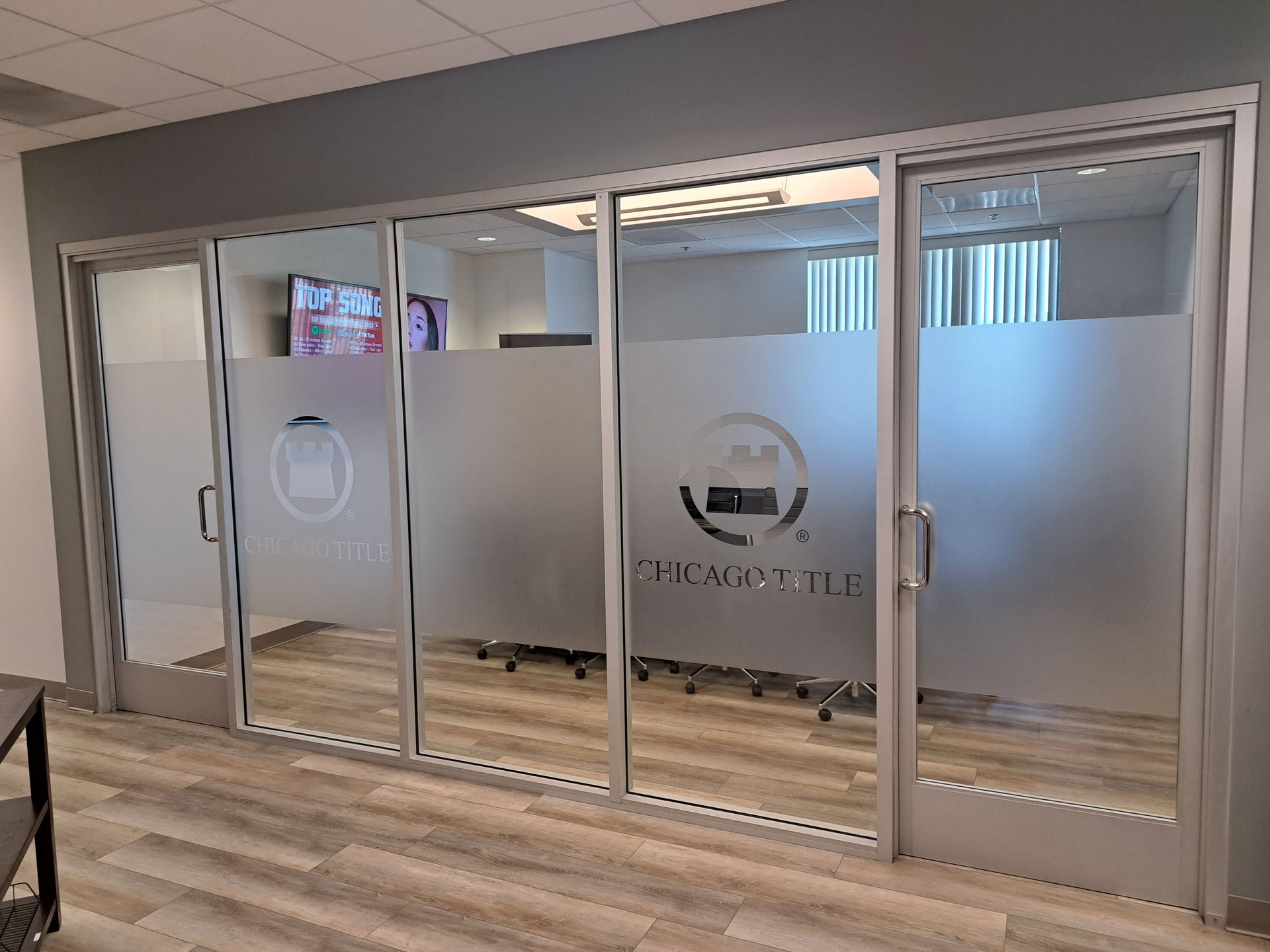 Frosted glass office meeting room with sliding doors and wood-look flooring.