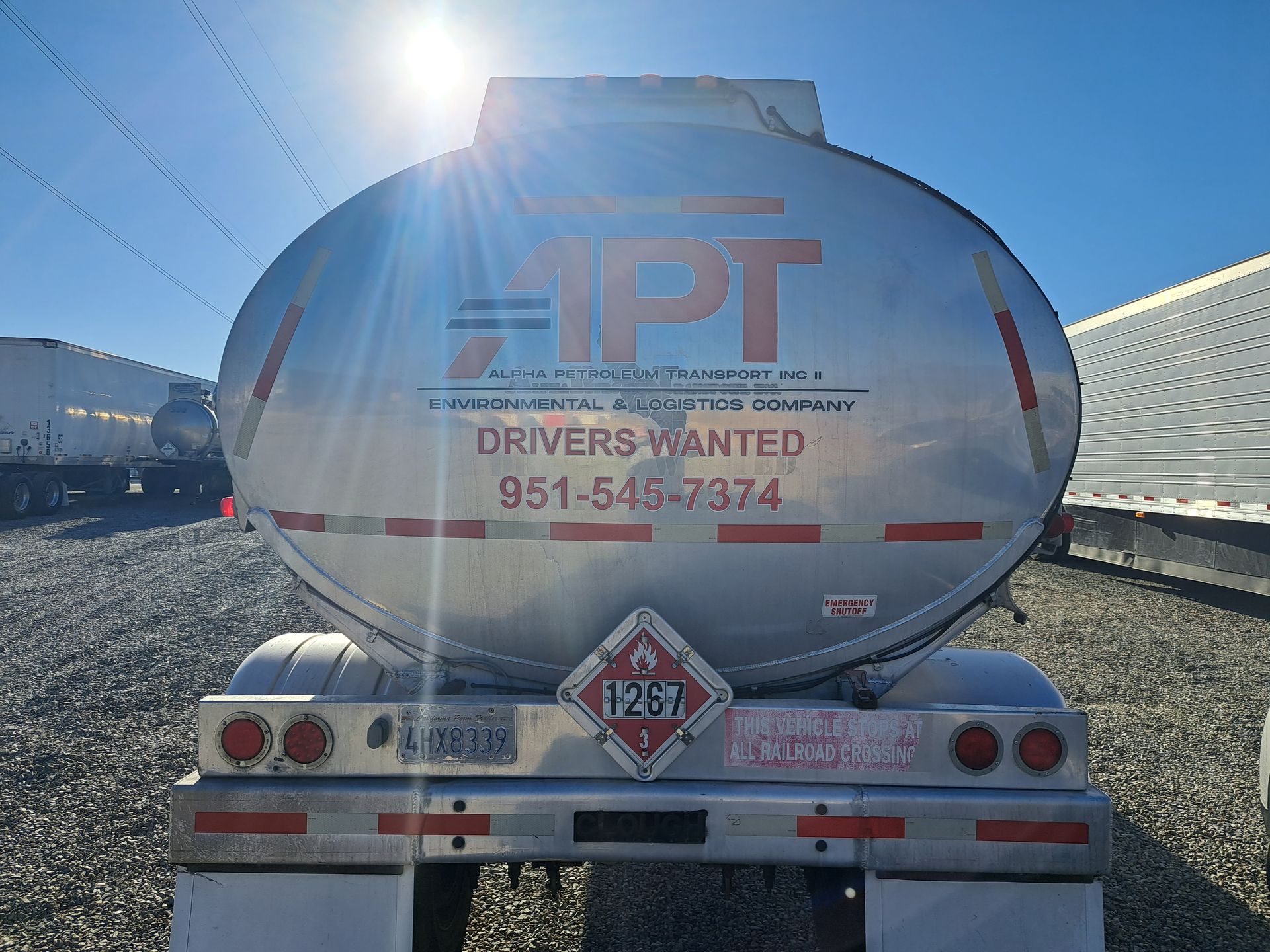 Rear view of a white tanker truck with company lettering and phone number in a snowy lot