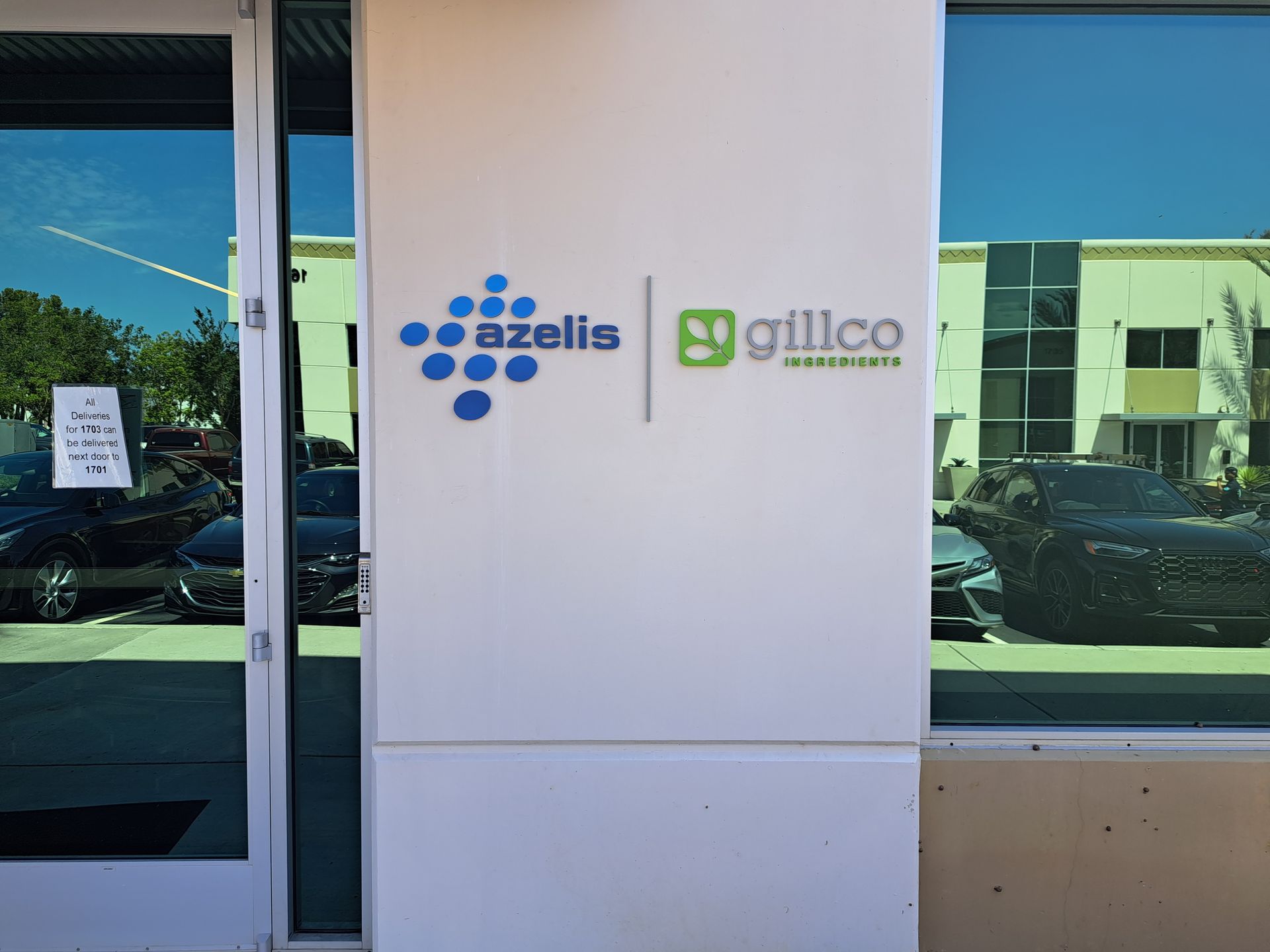 Exterior storefront with Azelis and Gilco logos on a white panel between glass windows.