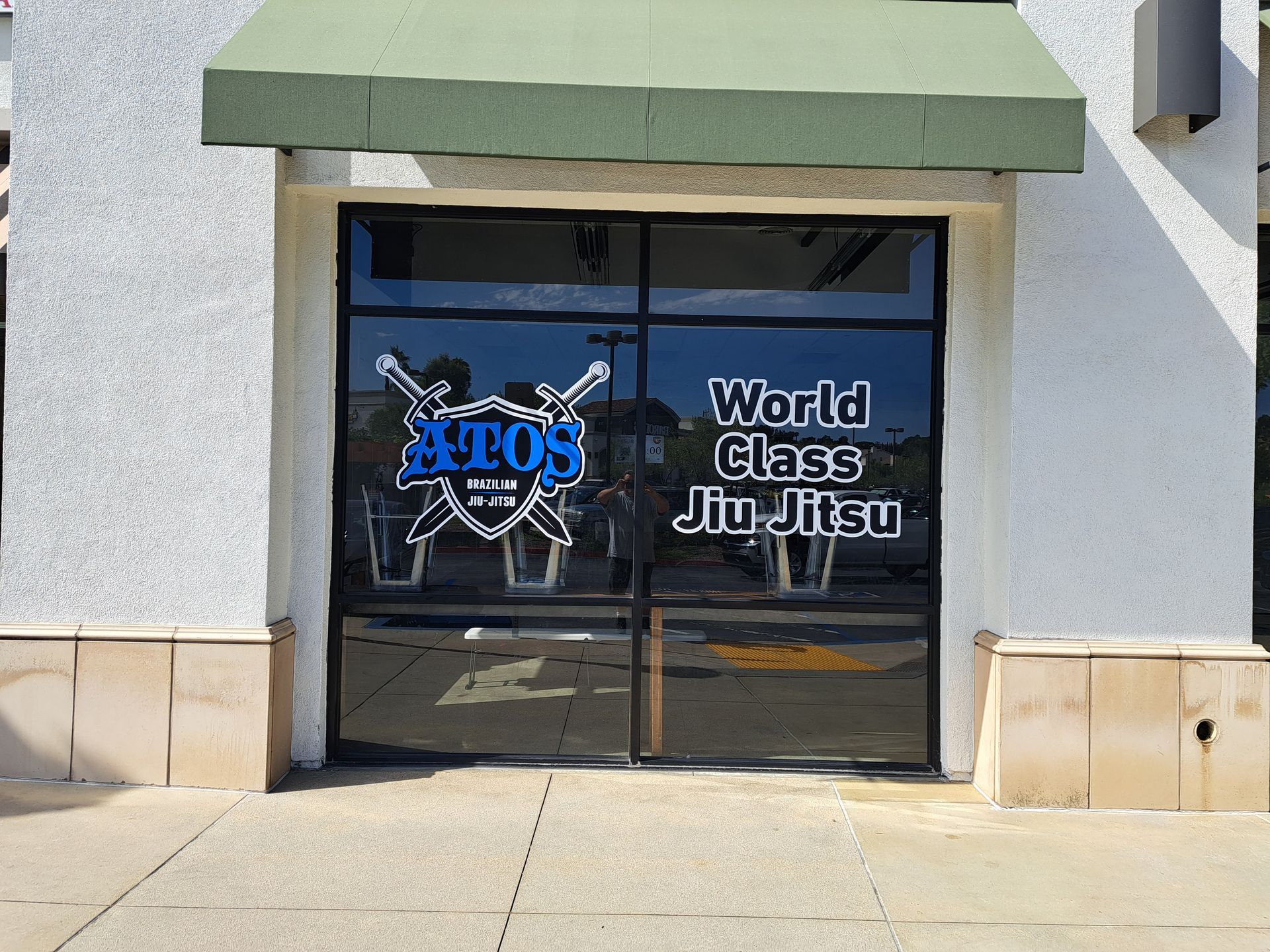 Storefront with glass doors labeled “World Class Jiu Jitsu” and “Axeos” under a green awning.