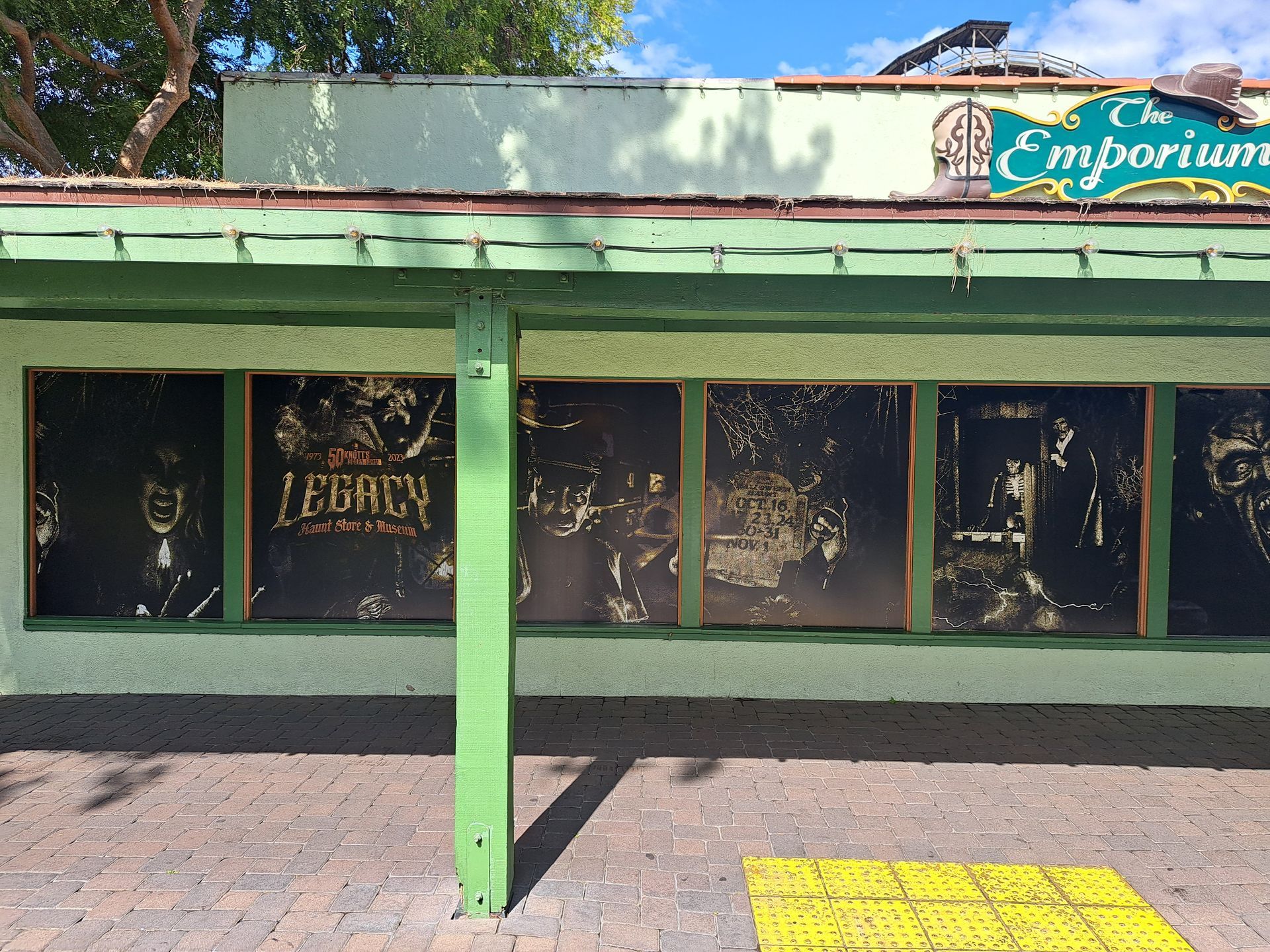 Empty storefront with green facade, dark windows, and an “Emporium” sign above the entrance
