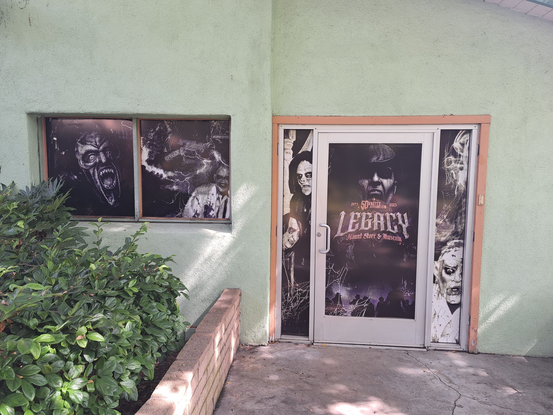 Gothic-themed storefront with dark poster-covered windows and a door labeled “LIBERTY” on a green wall