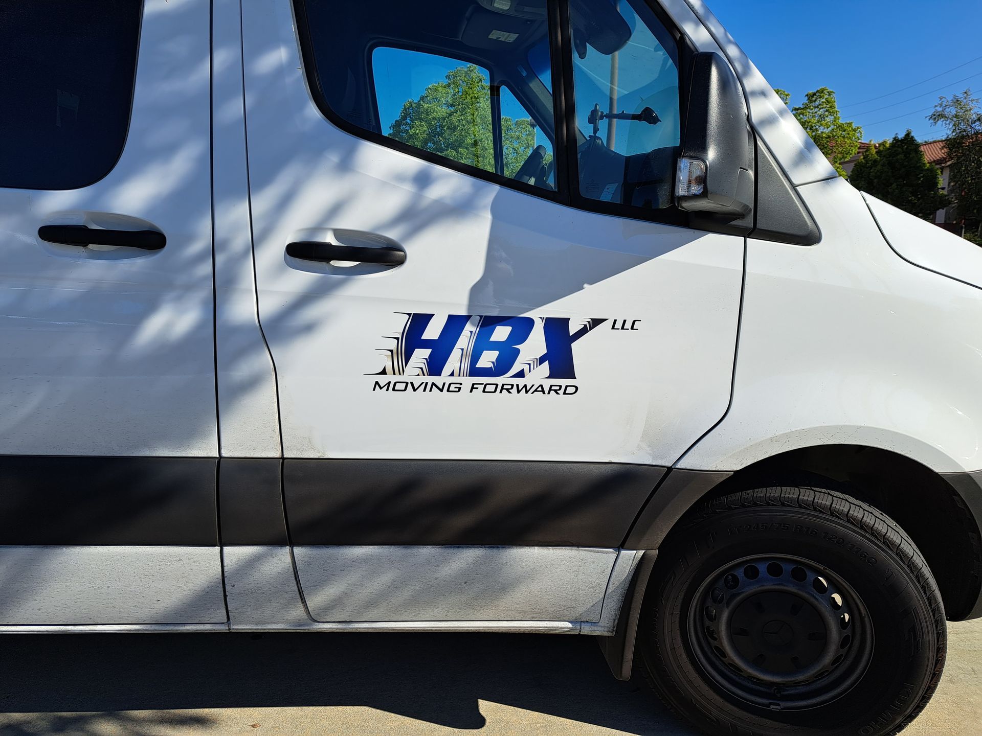 White HRX service van parked outdoors, side view with blue logo and black lower panel