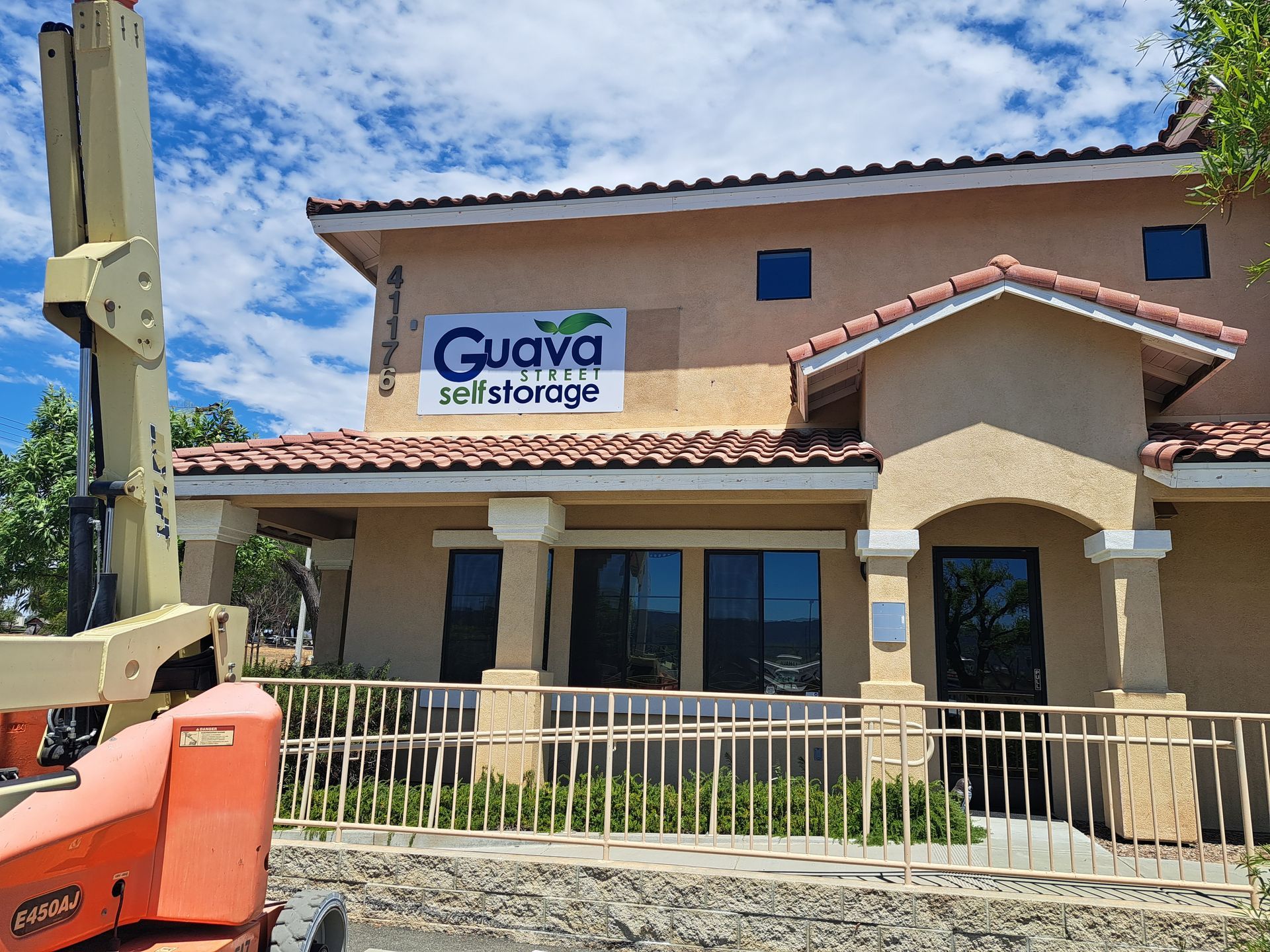 Guava Self Storage building with stucco facade and orange forklift in front under a blue sky