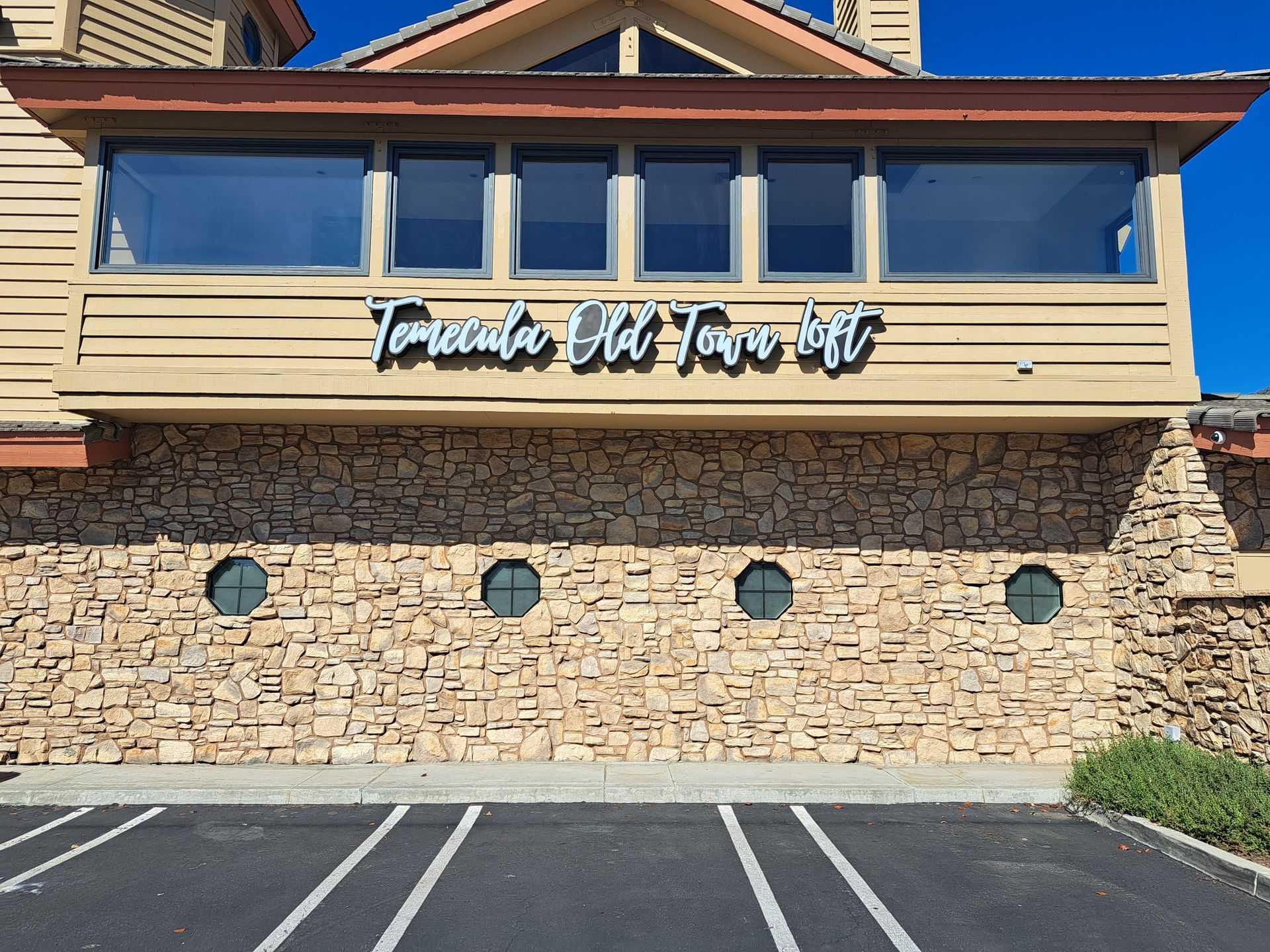 Stone-front building with blue windows and a sign reading “Toscana at 1000 West.”