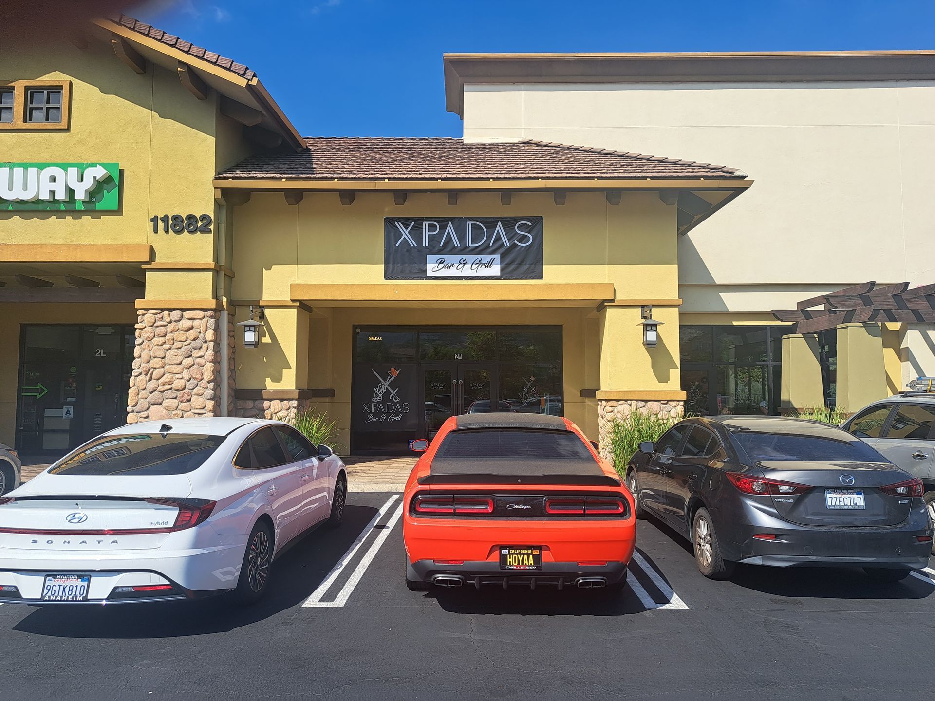 Three parked cars outside a yellow storefront with a Japanese sign.