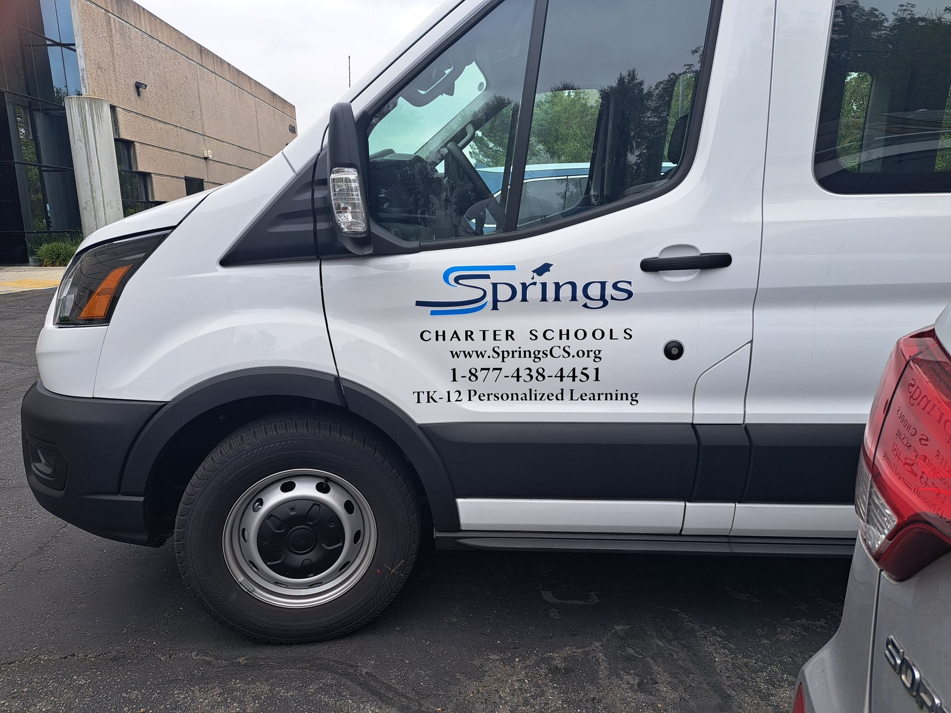 White Springs service van with company logo and phone number parked beside a red car.