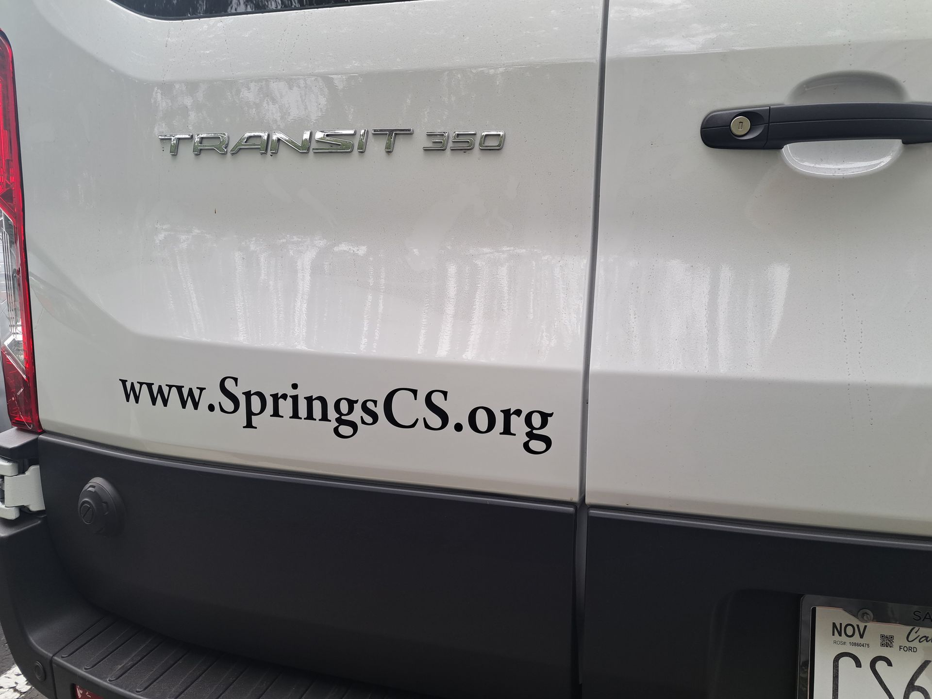 Rear of a white minivan with www.SpringsCS.org printed on the back hatch