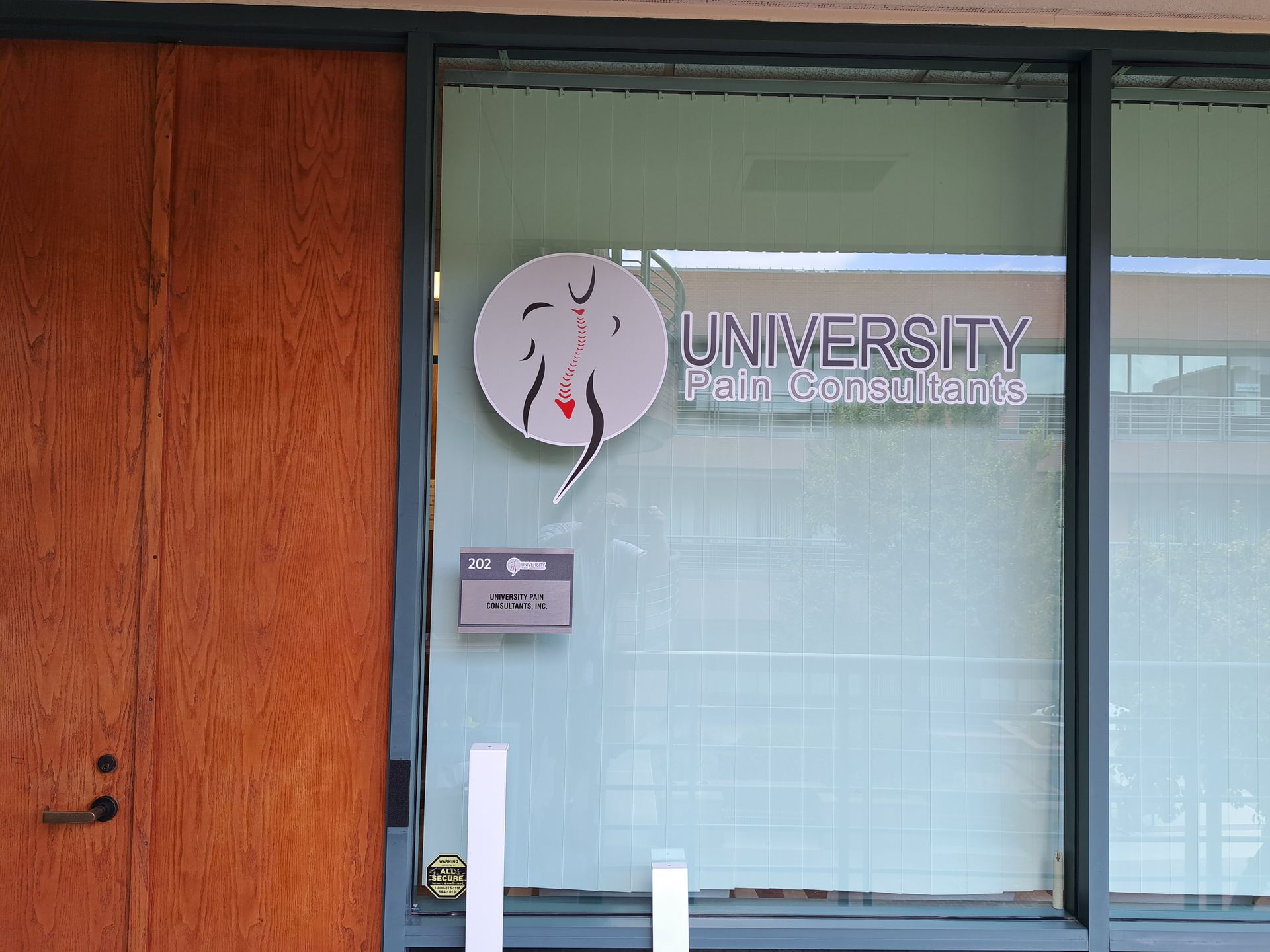 Office door with University logo on glass beside a wooden wall