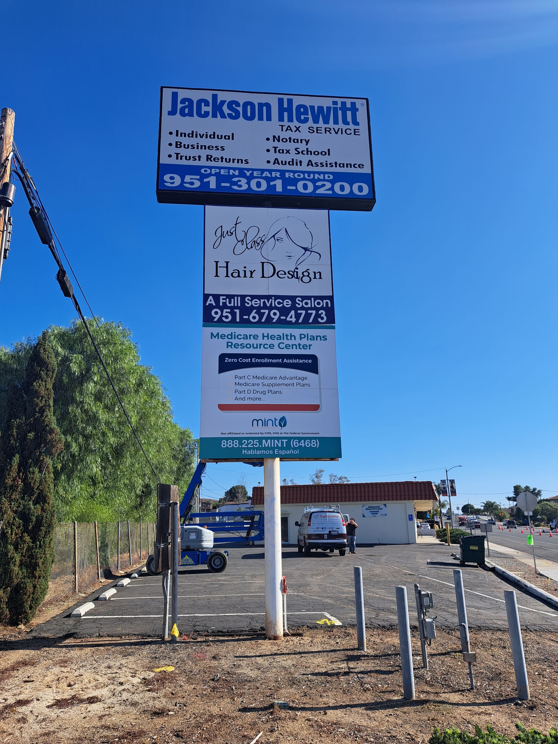 Jackson Hewitt tax sign beside a gravel lot under a clear blue sky