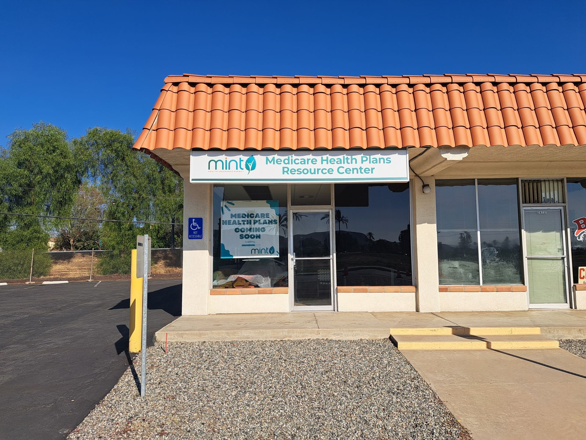 Front entrance of a community health center with terracotta roof, glass doors, and wheelchair access sign