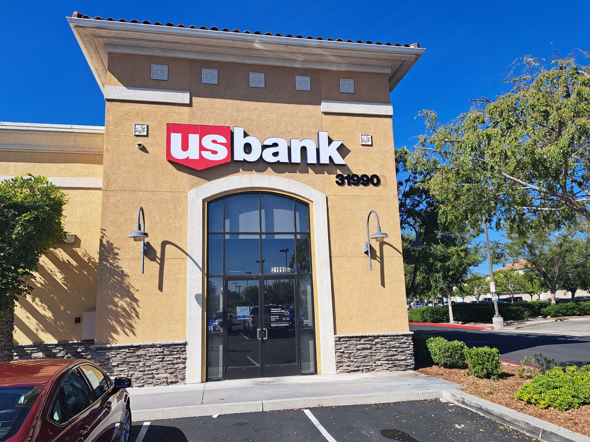 US Bank branch storefront with tan stucco exterior, arched entrance, and blue sky