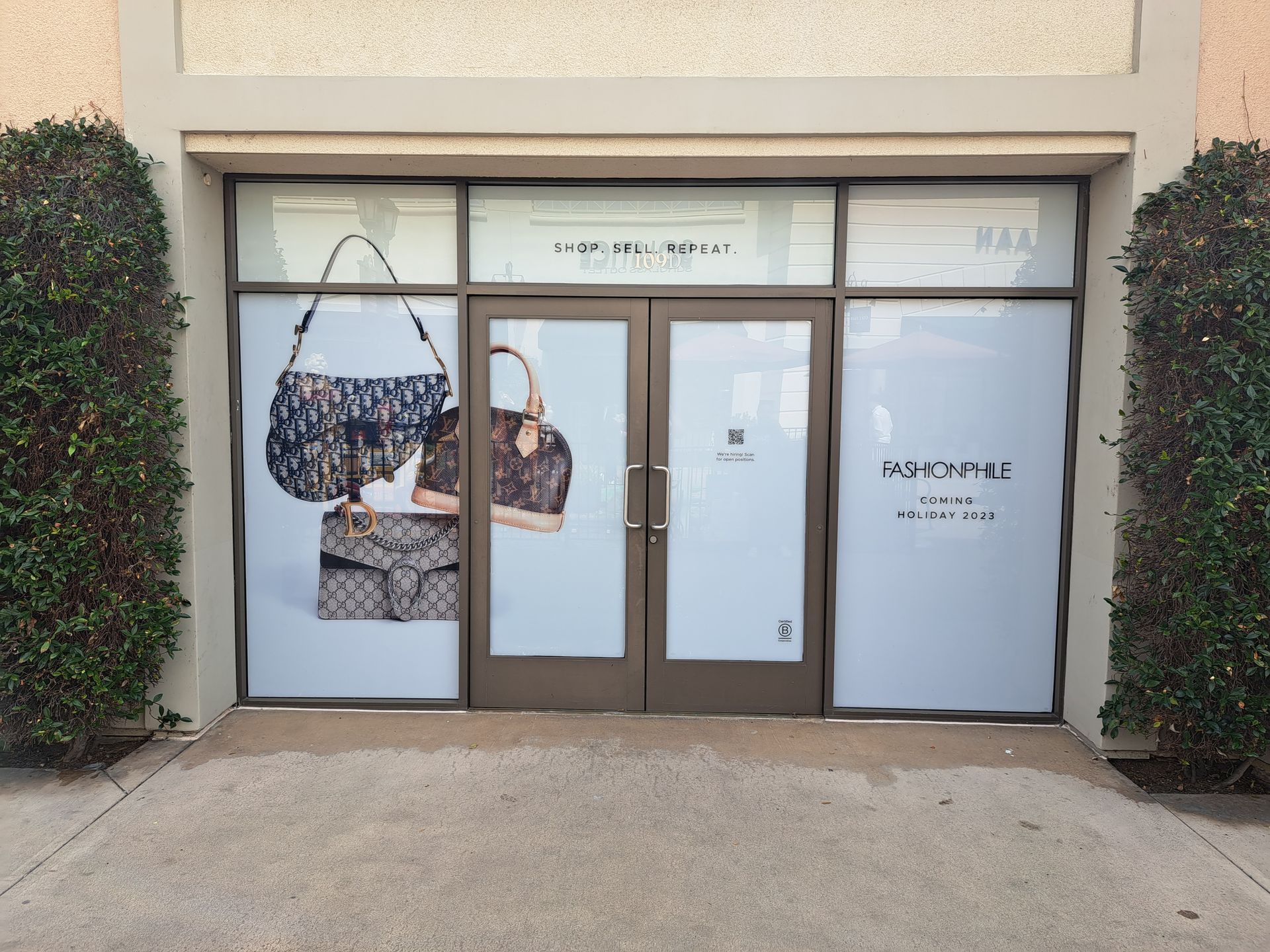 Storefront with a glass door and windows, displaying handbags and a “HOTEL” sign