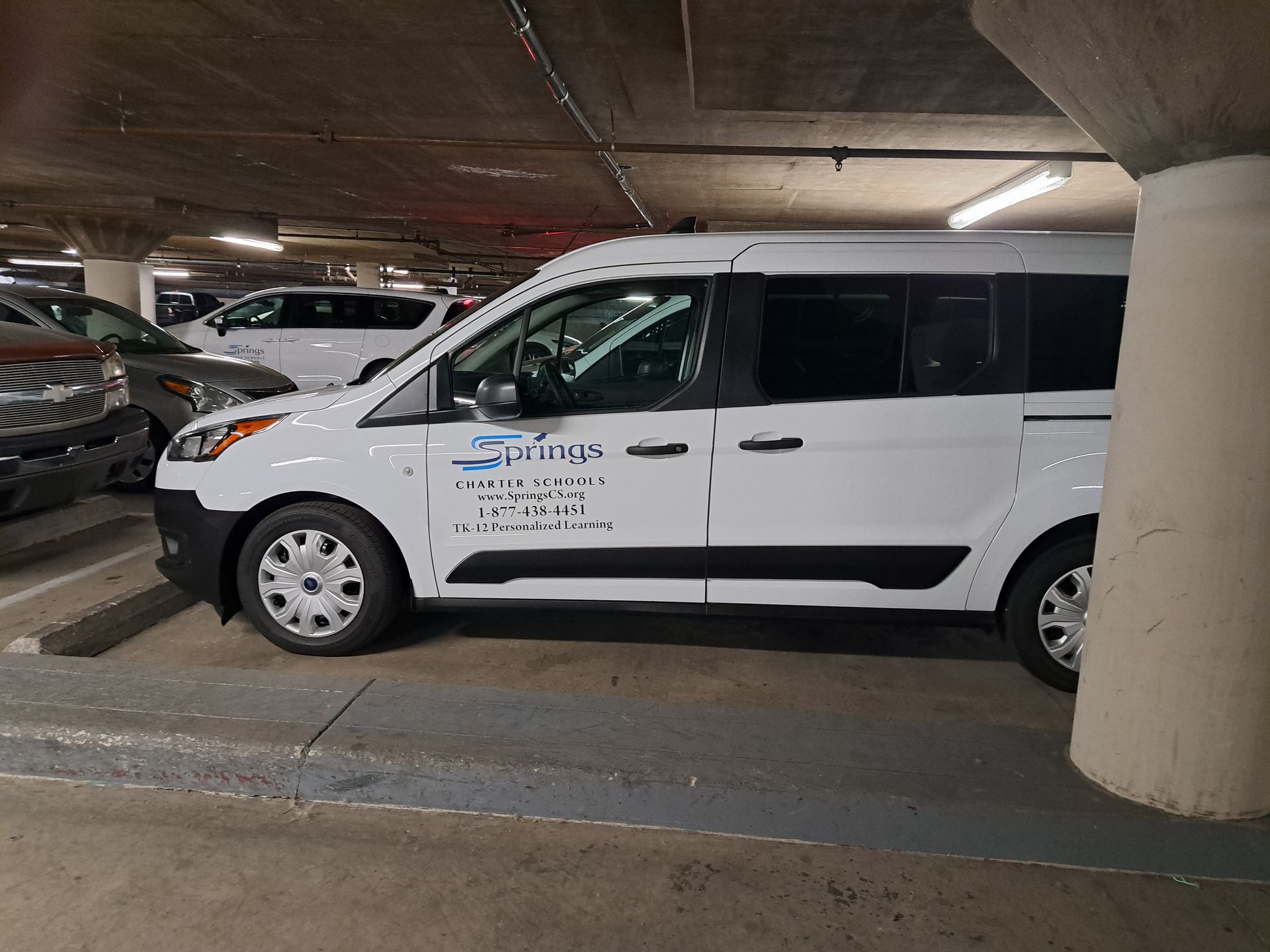 White van parked in an underground garage beside a concrete pillar