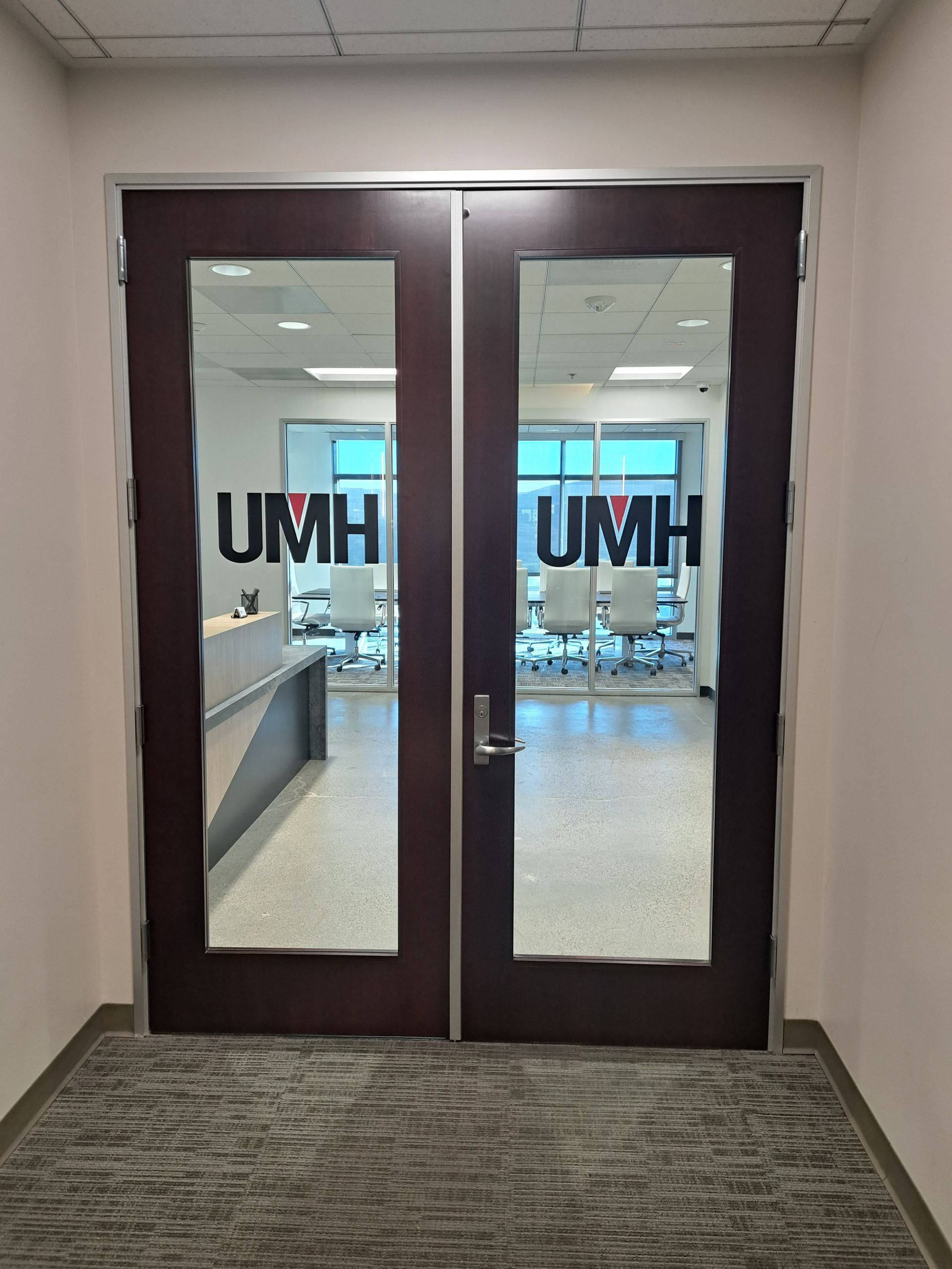 Glass double doors with UMH logos, opening into a bright office or clinic waiting area