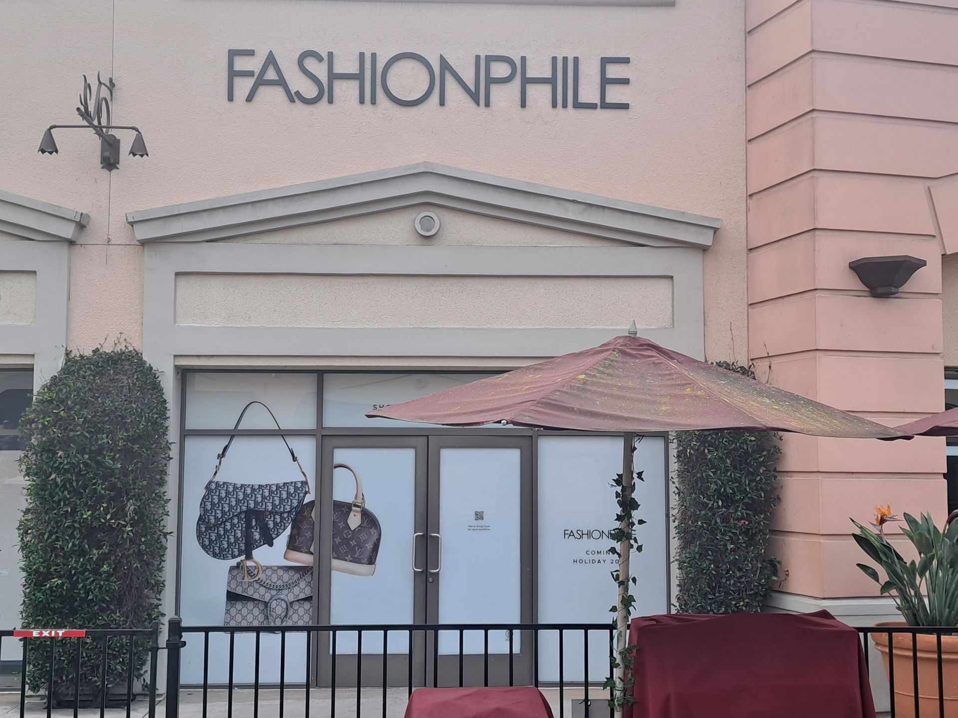 FashionPhile storefront with pink facade, glass entrance, and patio umbrella in front