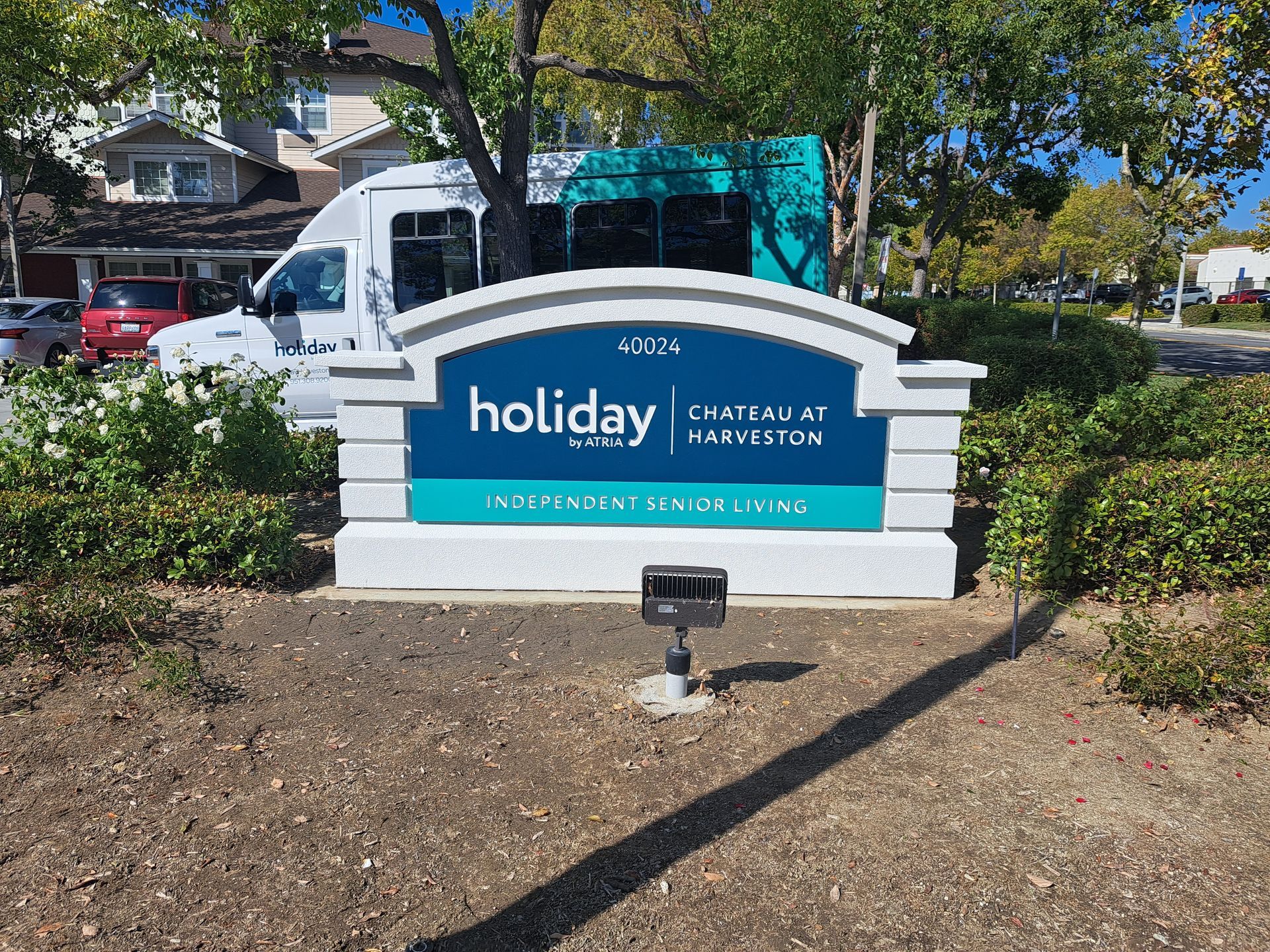 Holiday Inn sign with teal panel and truck in a landscaped parking lot